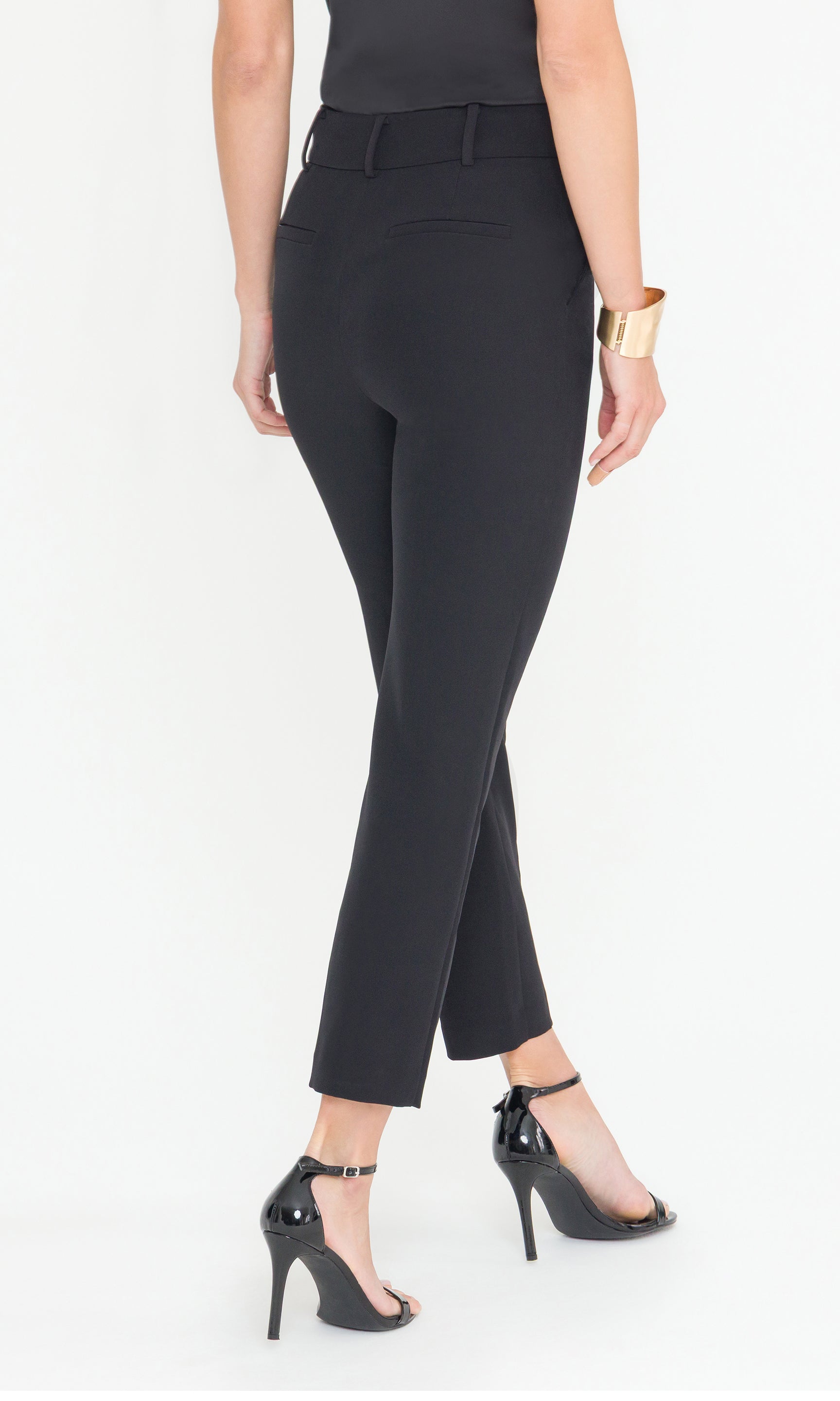Back view of black pants worn by a person on a white background