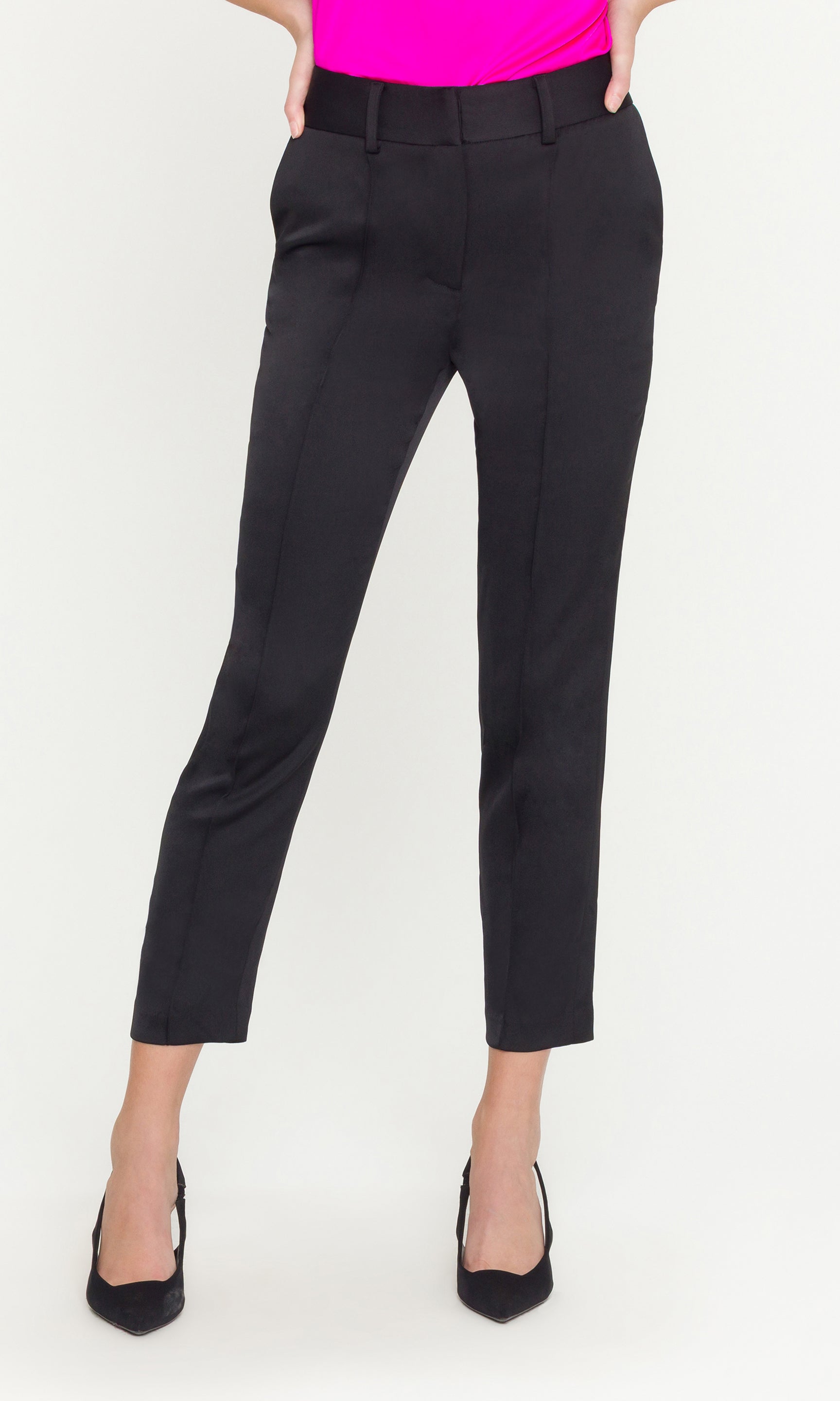 Person wearing black pants and a bright pink top on a white background