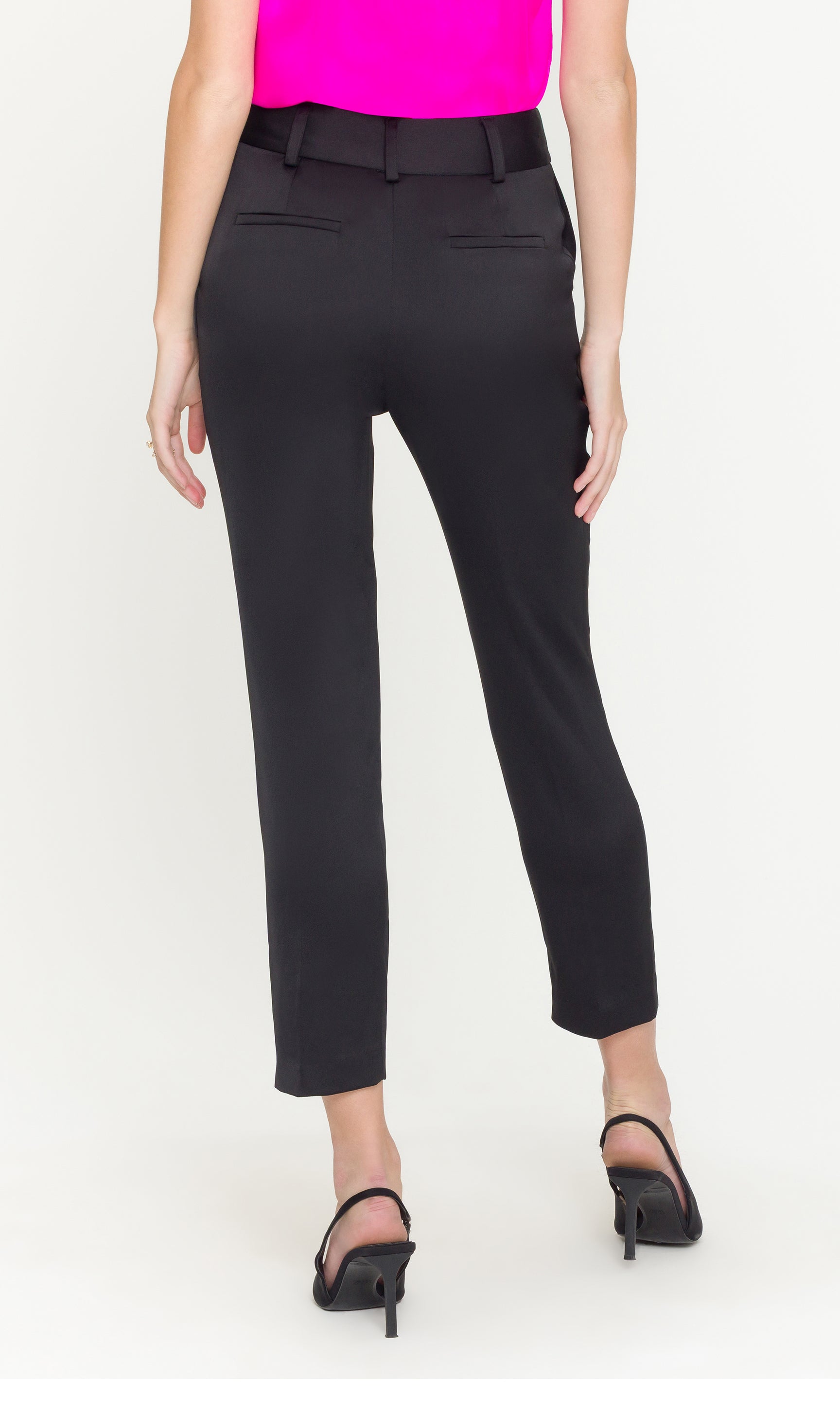 Person wearing black pants and a bright pink top on a white background