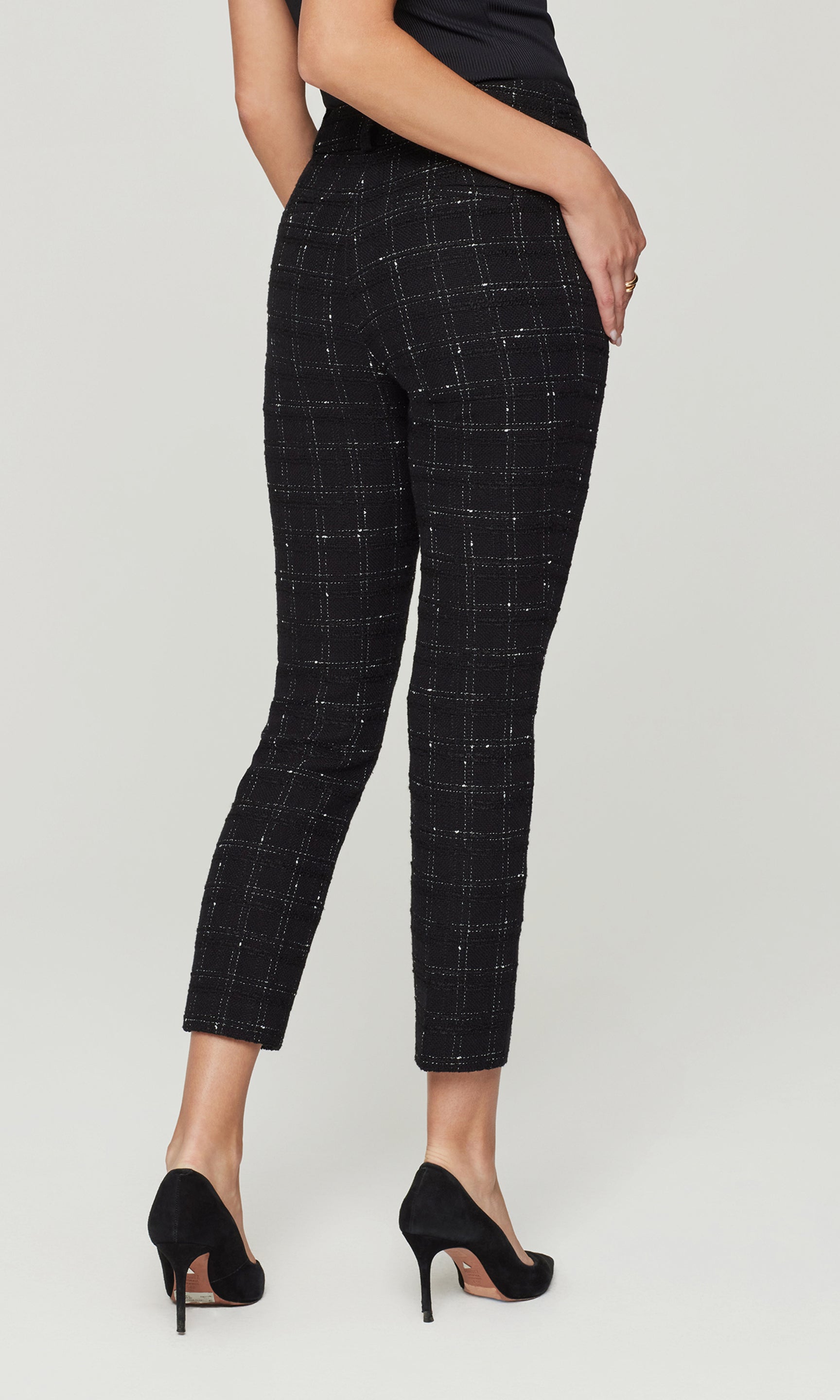 Back view of black checkered pants worn by a person on a white background