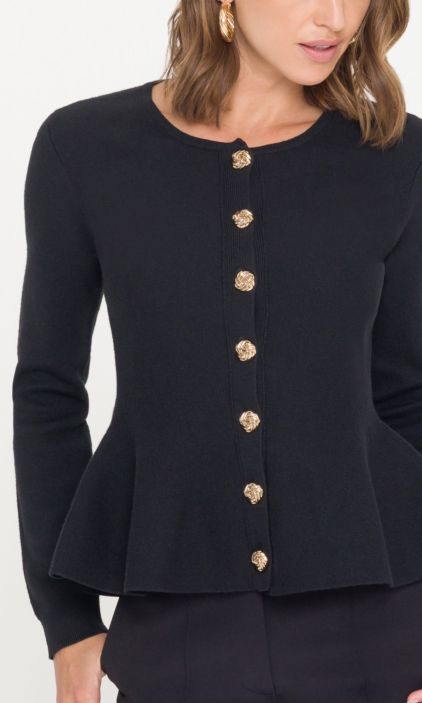 Detail crop of black peplum cardigan with gold buttons down the front on a white background
