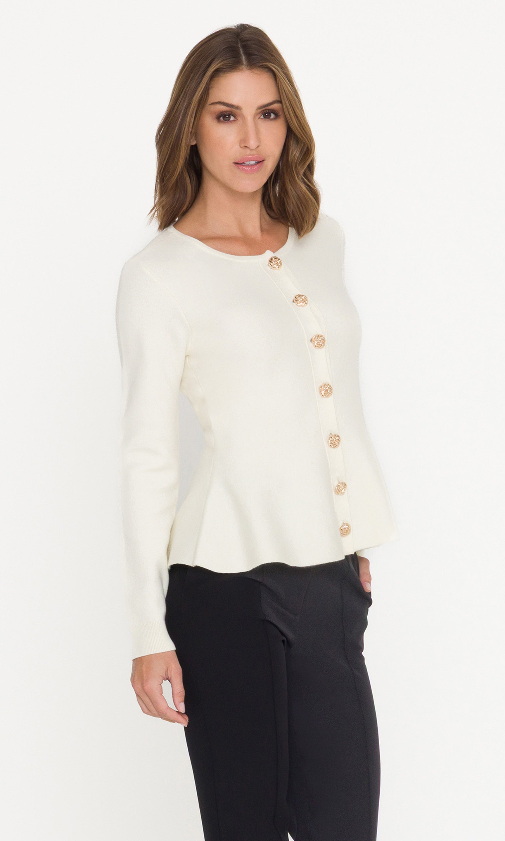 Side view of woman wearing a cream cardigan with gold buttons on a white background