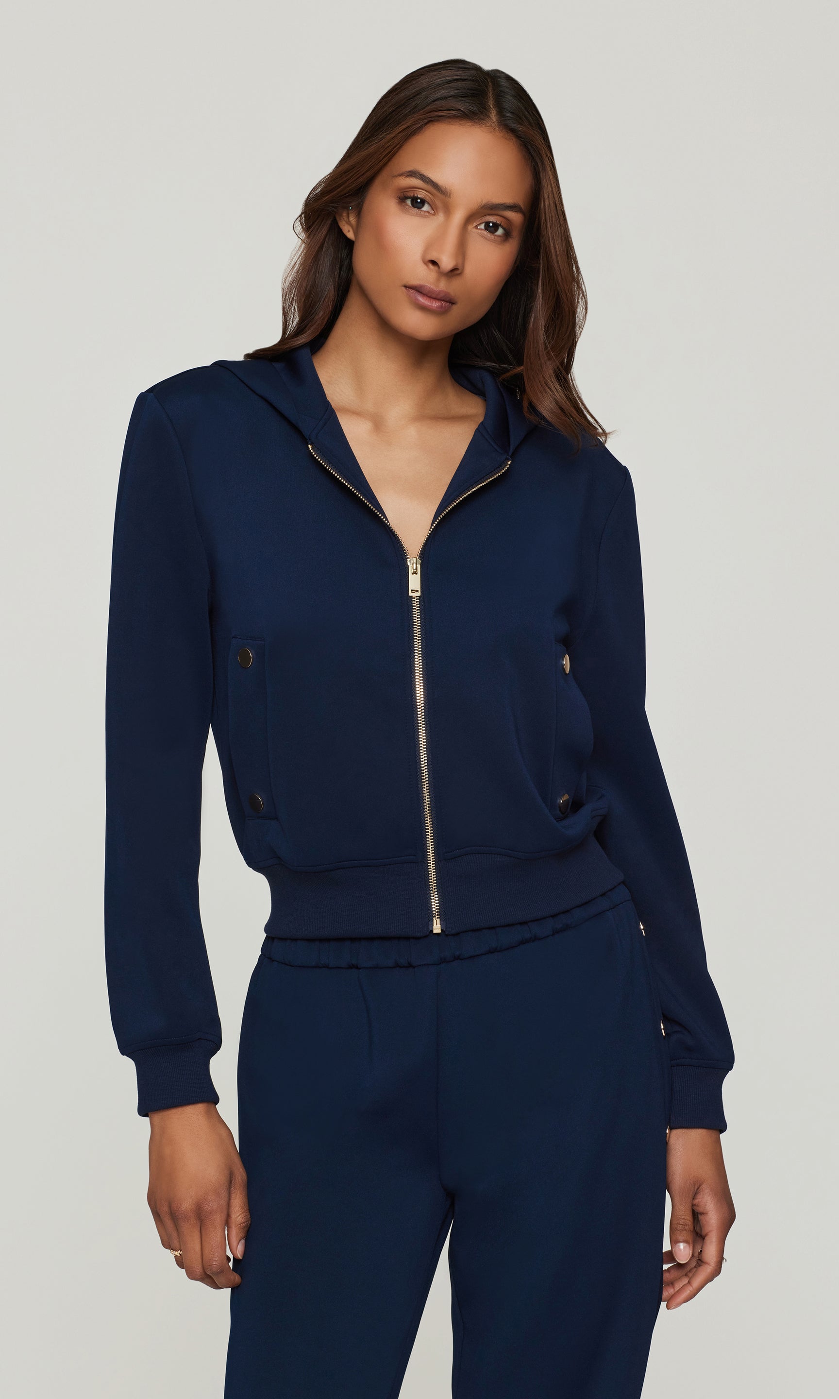 Woman wearing a navy blue tracksuit on a light gray background
