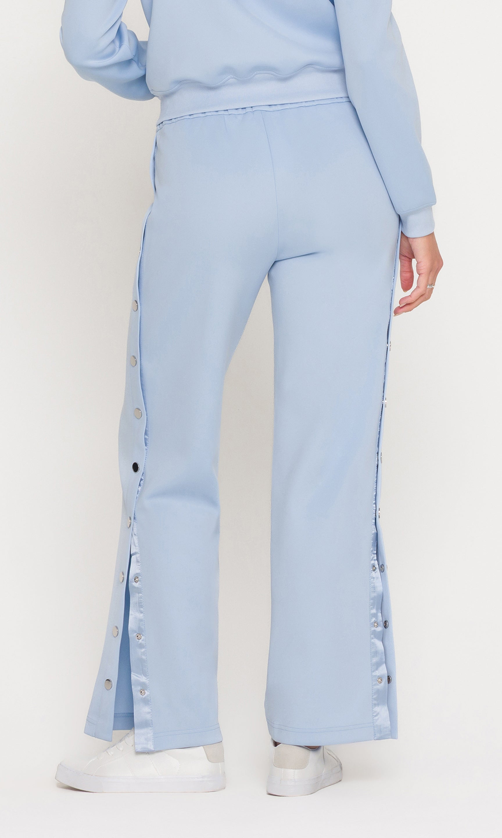 Back view of light blue pants with button details on a white background