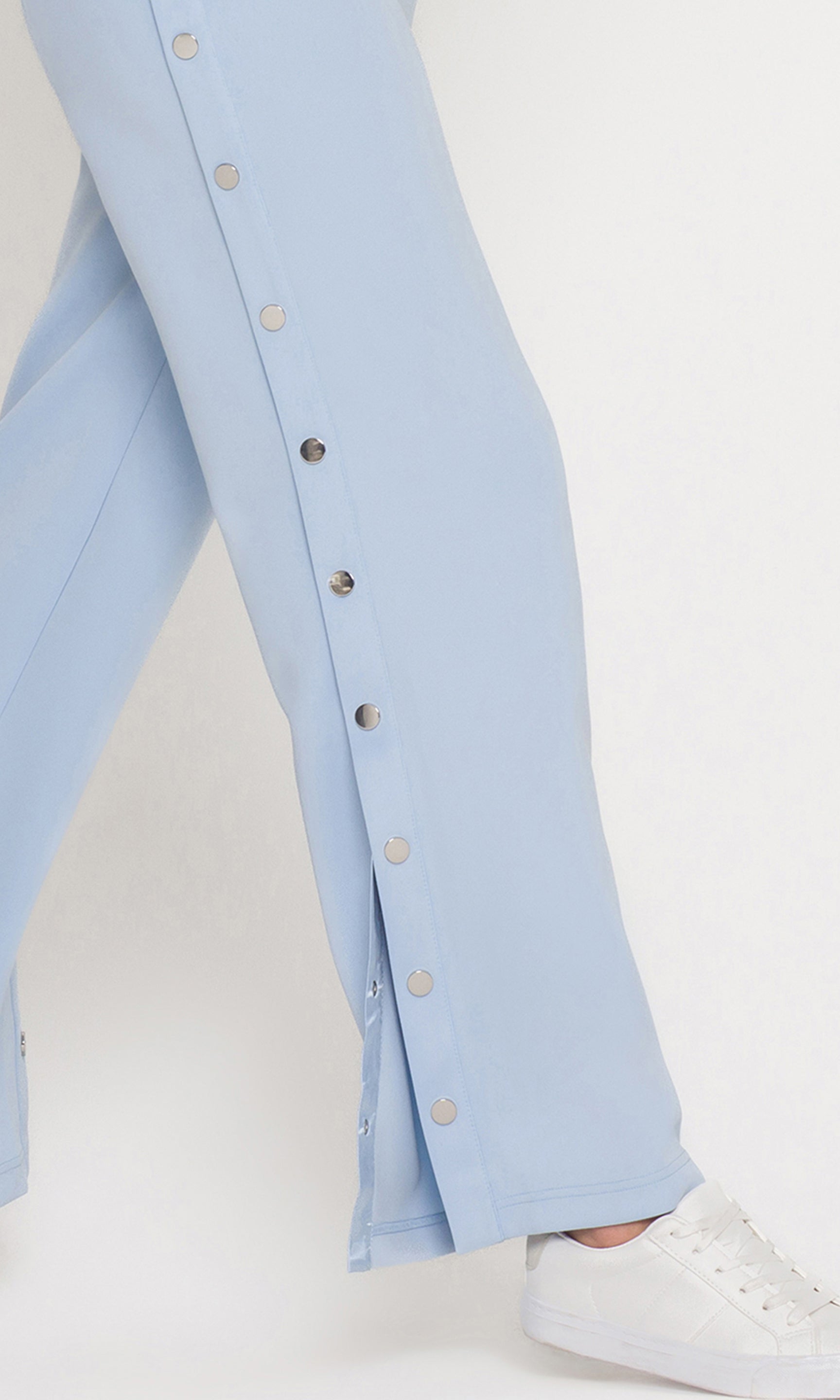 Close-up of light blue pants with button details on a white background