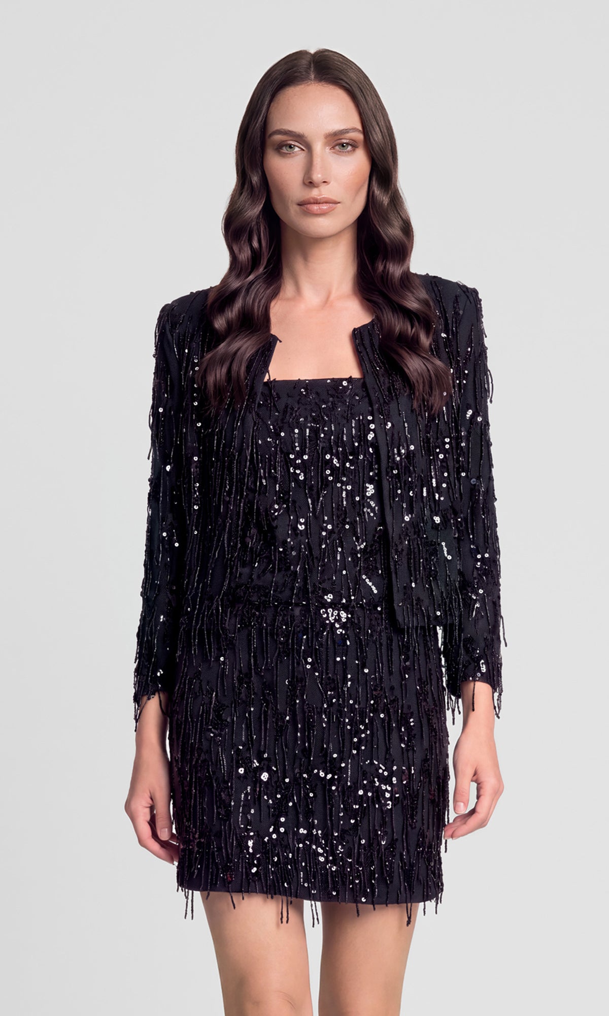 Model wearing a black fringe sequins jacket over a matching fringe sequins cami and skirt.