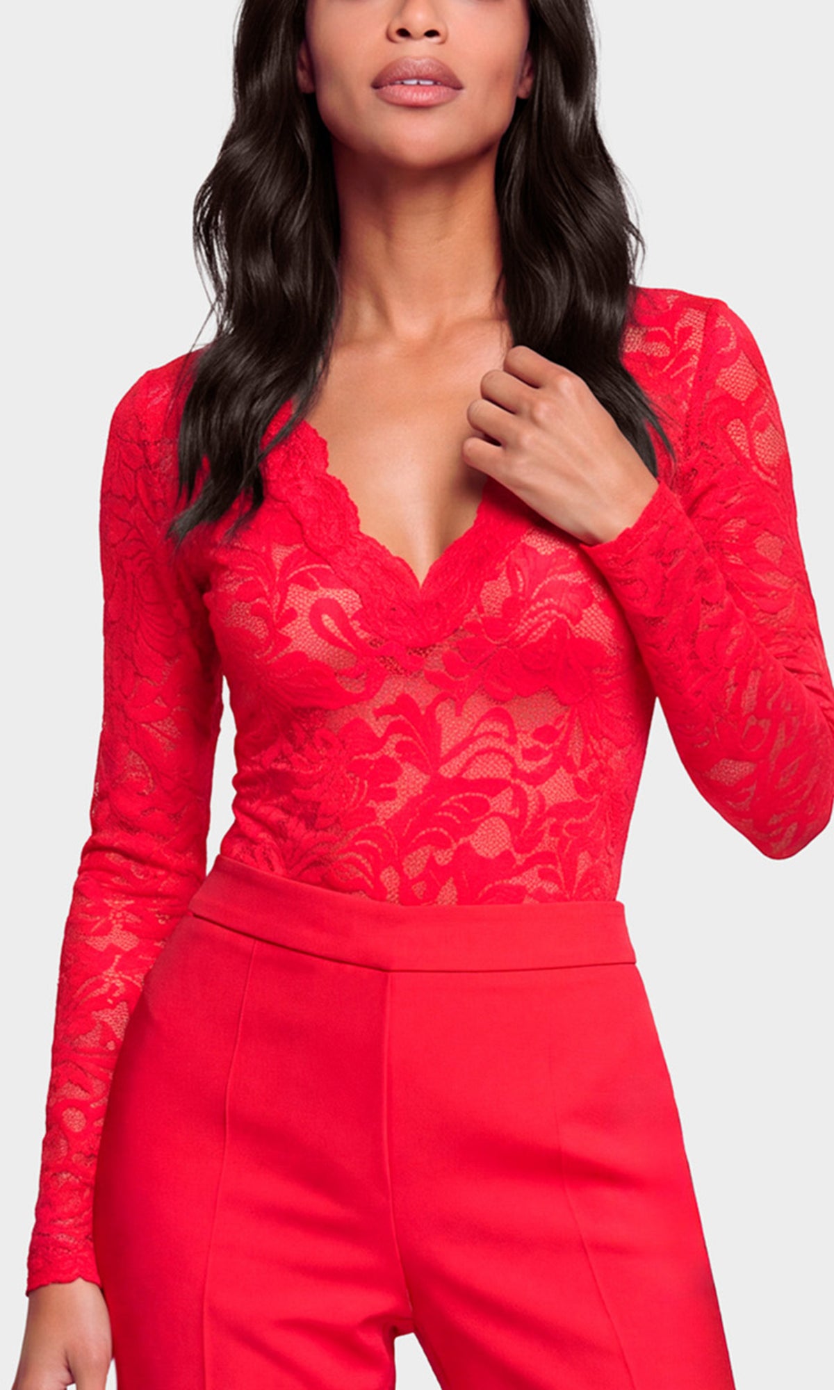 Close-up of a bright red lace long-sleeve top with a deep V-neck and matching red high-waisted trousers.