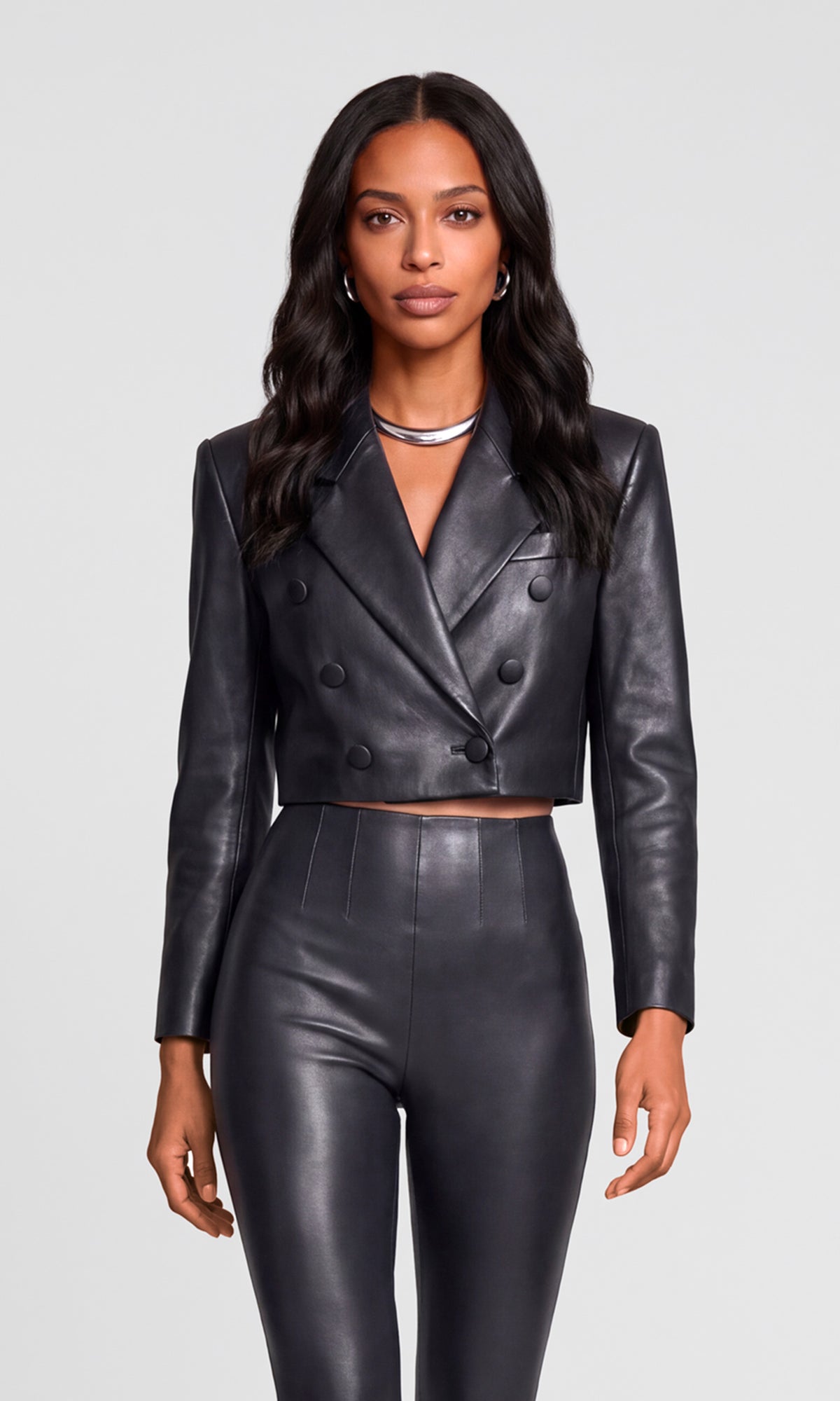 Model wearing a black faux-leather double-breasted blazer and matching high-waisted cropped pants.