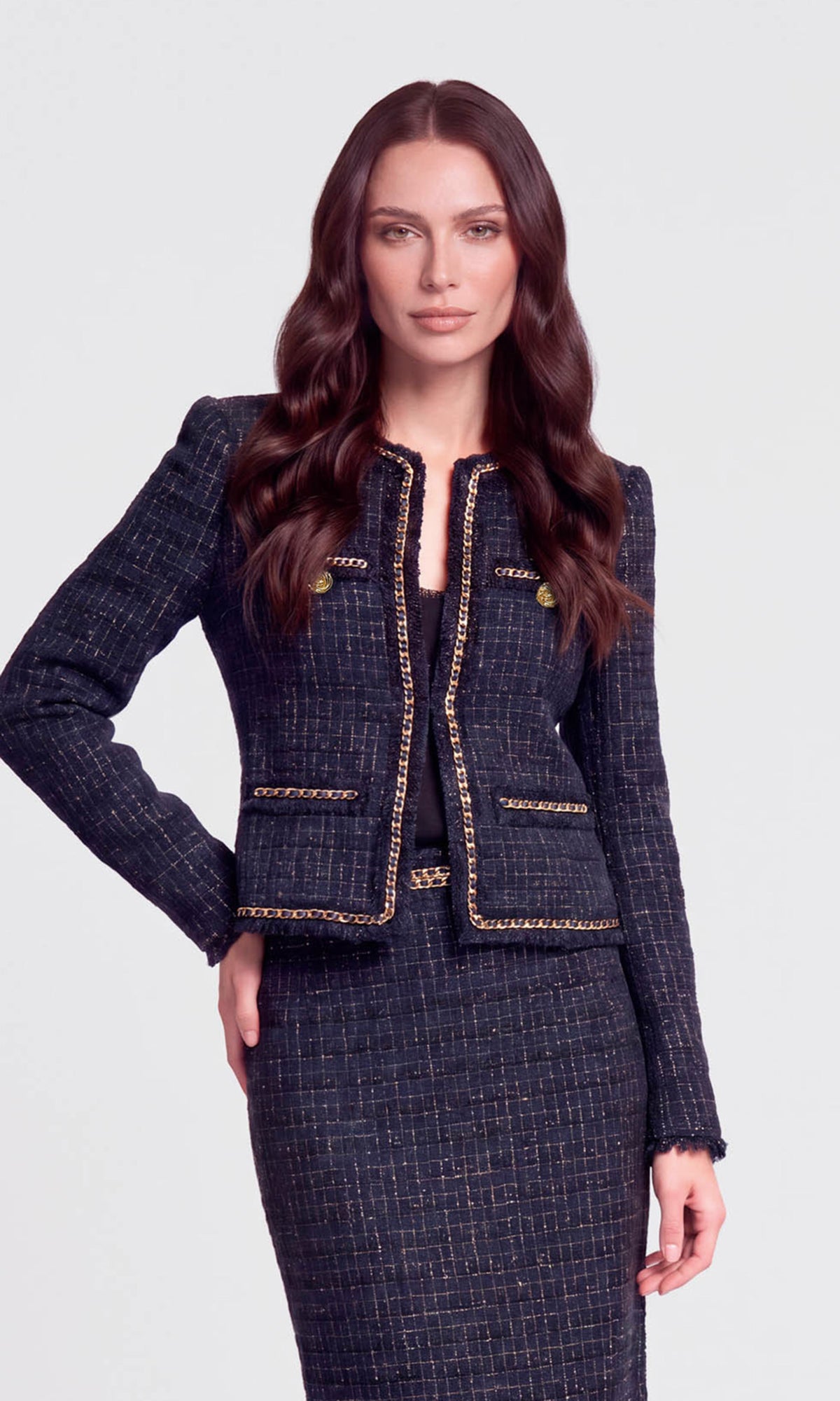 Model wearing a navy tweed jacket with gold accents and a matching skirt.