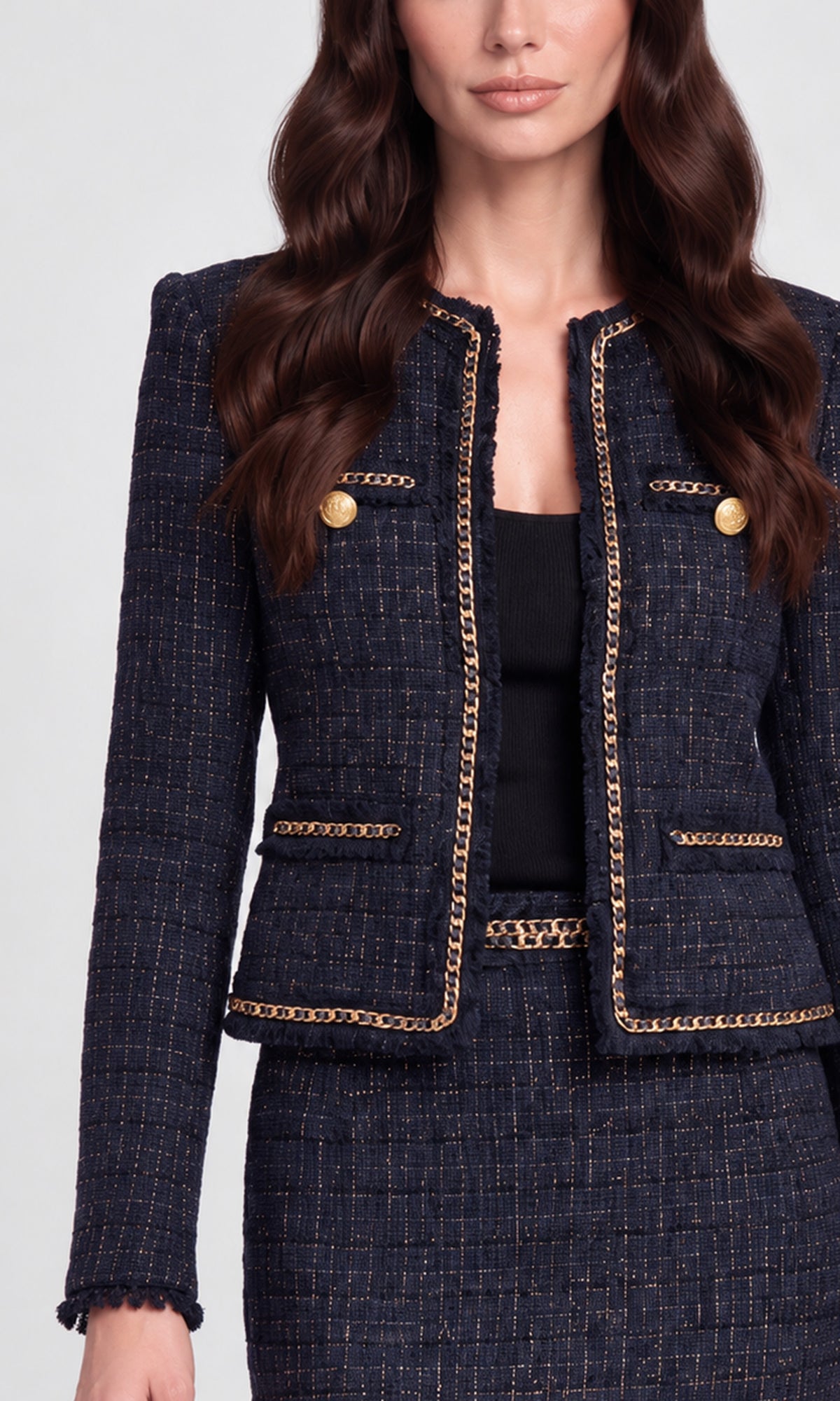 Close-up of a tailored navy tweed blazer with gold chain trim and gold buttons, paired with a matching skirt.