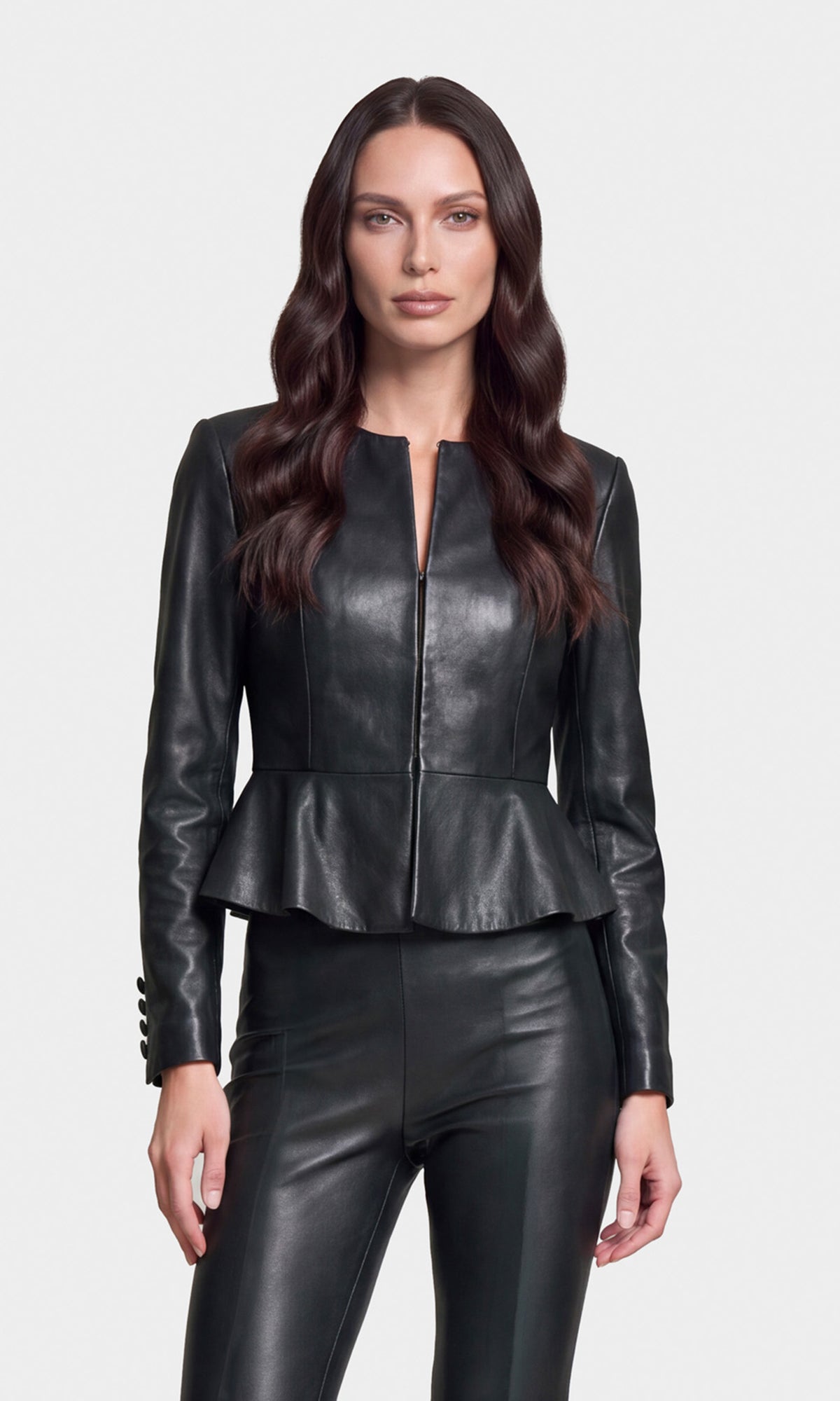 Model wearing a black faux-leather cropped jacket with a front zipper and peplum waist, paired with matching black leather-look pants.