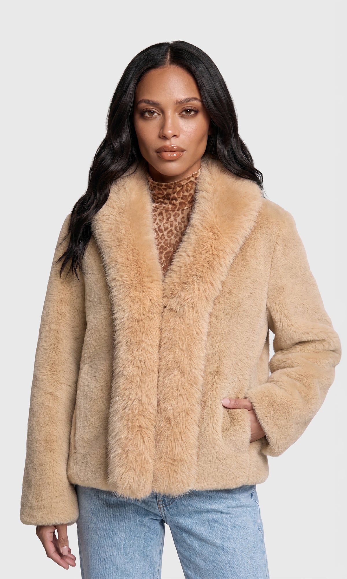 Model wearing a beige faux fur jacket with a wide collar, worn over a leopard print top and blue jeans.
