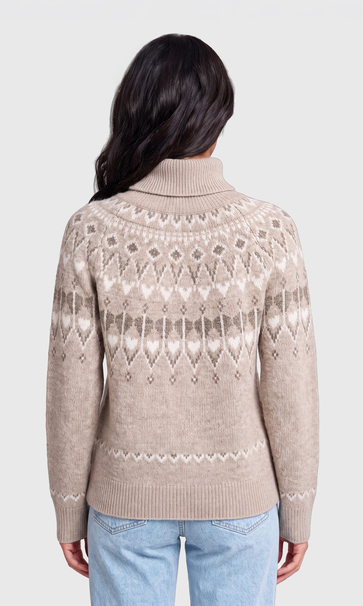 Back view of model wearing a beige turtleneck sweater with a white and gray geometric Fair Isle pattern, paired with light blue jeans.