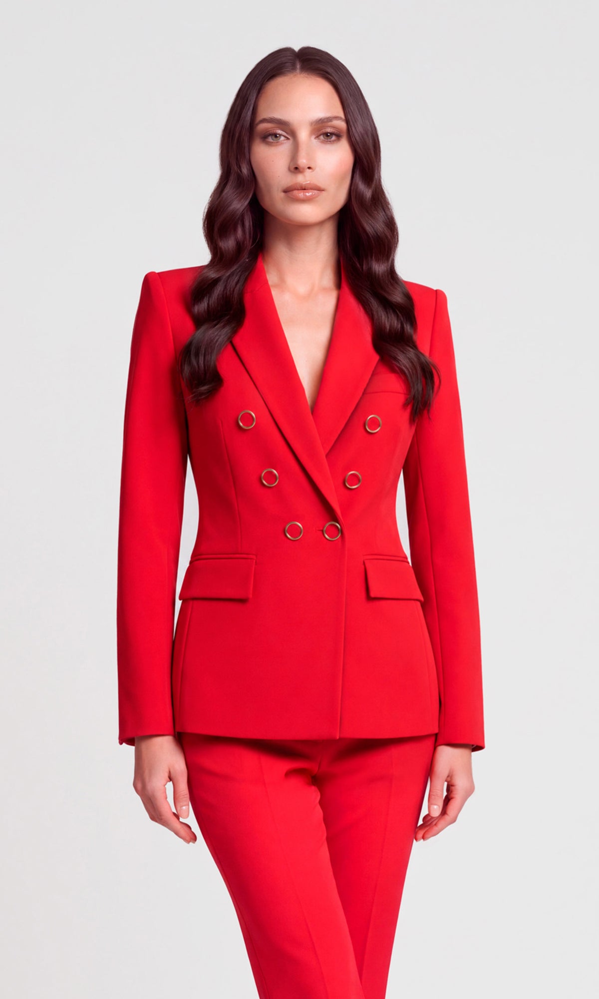 A woman modeling a bright red double-breasted blazer and matching red trousers.