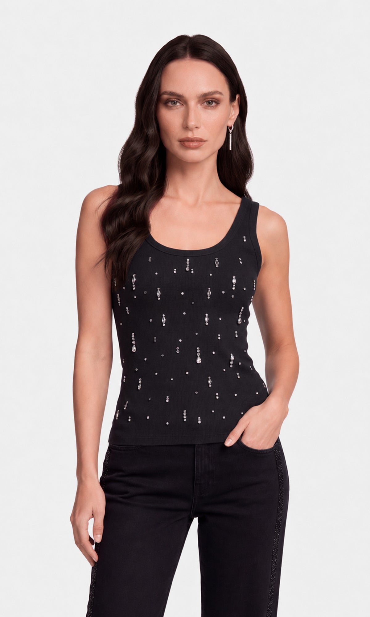 A woman modeling a black sleeveless tank top with a vertical silver graphic print, paired with black jeans.