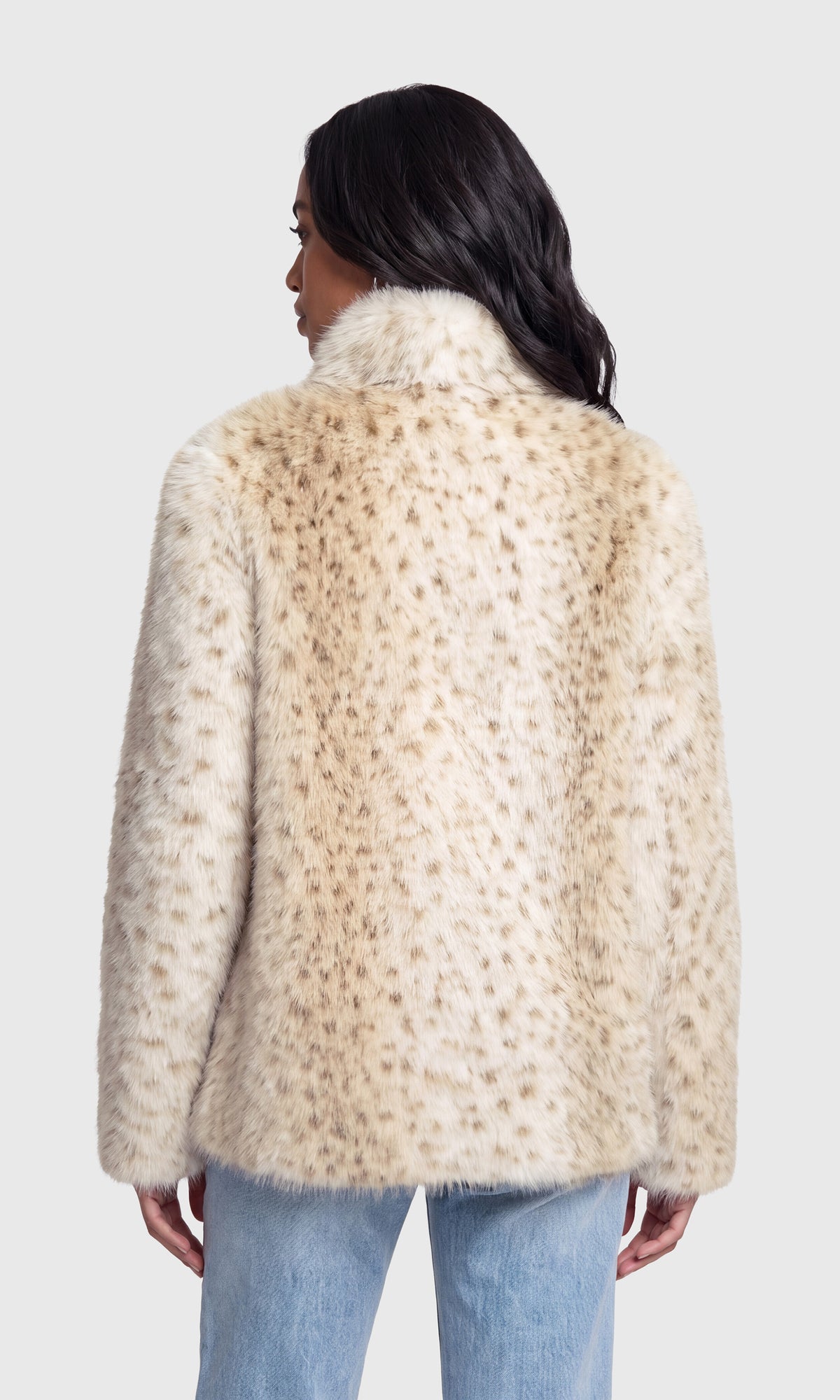 A woman shown from the back wearing a cream faux fur jacket with a tan leopard print pattern and light blue jeans.