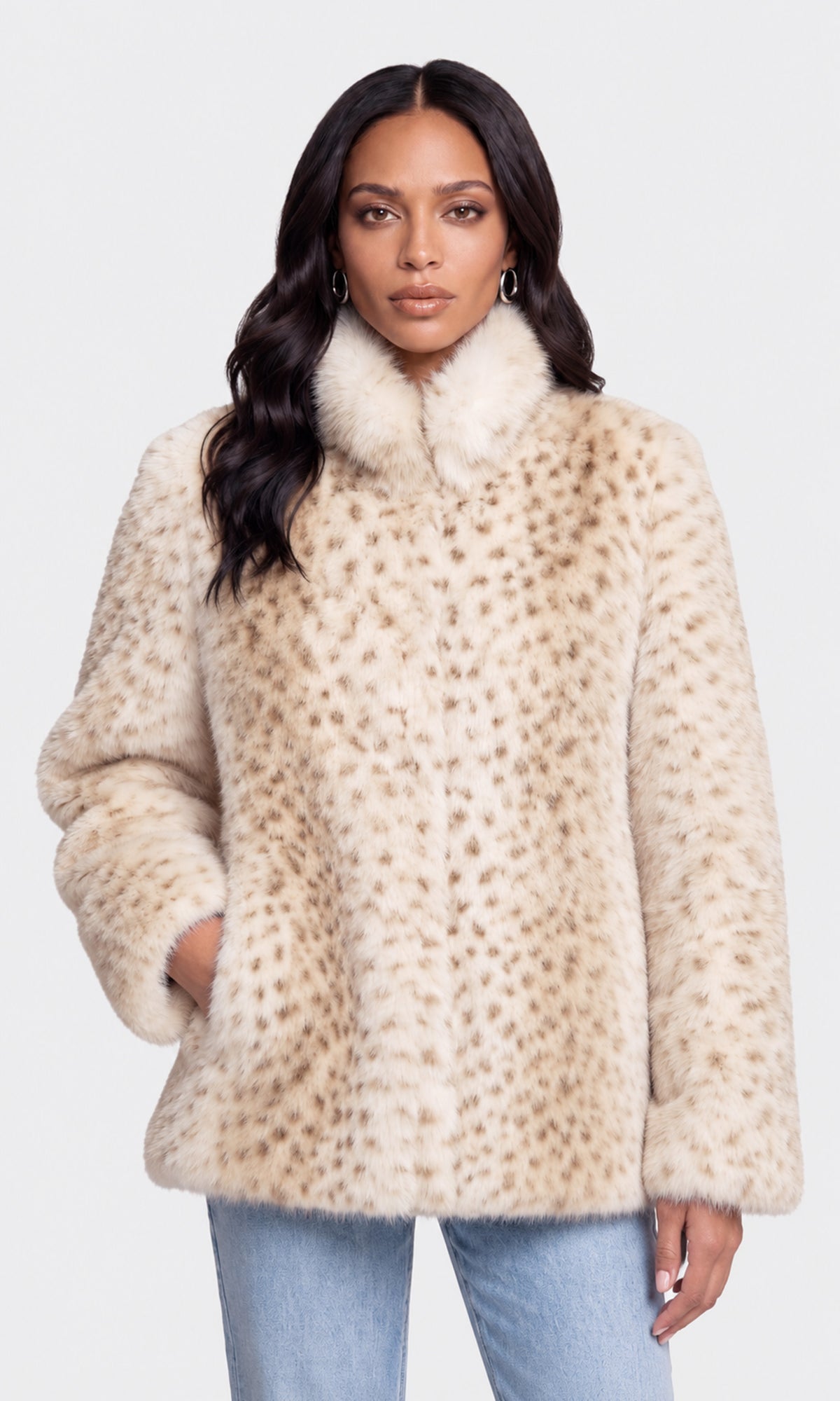 A woman modeling a beige faux fur jacket with a brown leopard print pattern and a high fluffy collar, paired with light blue jeans.