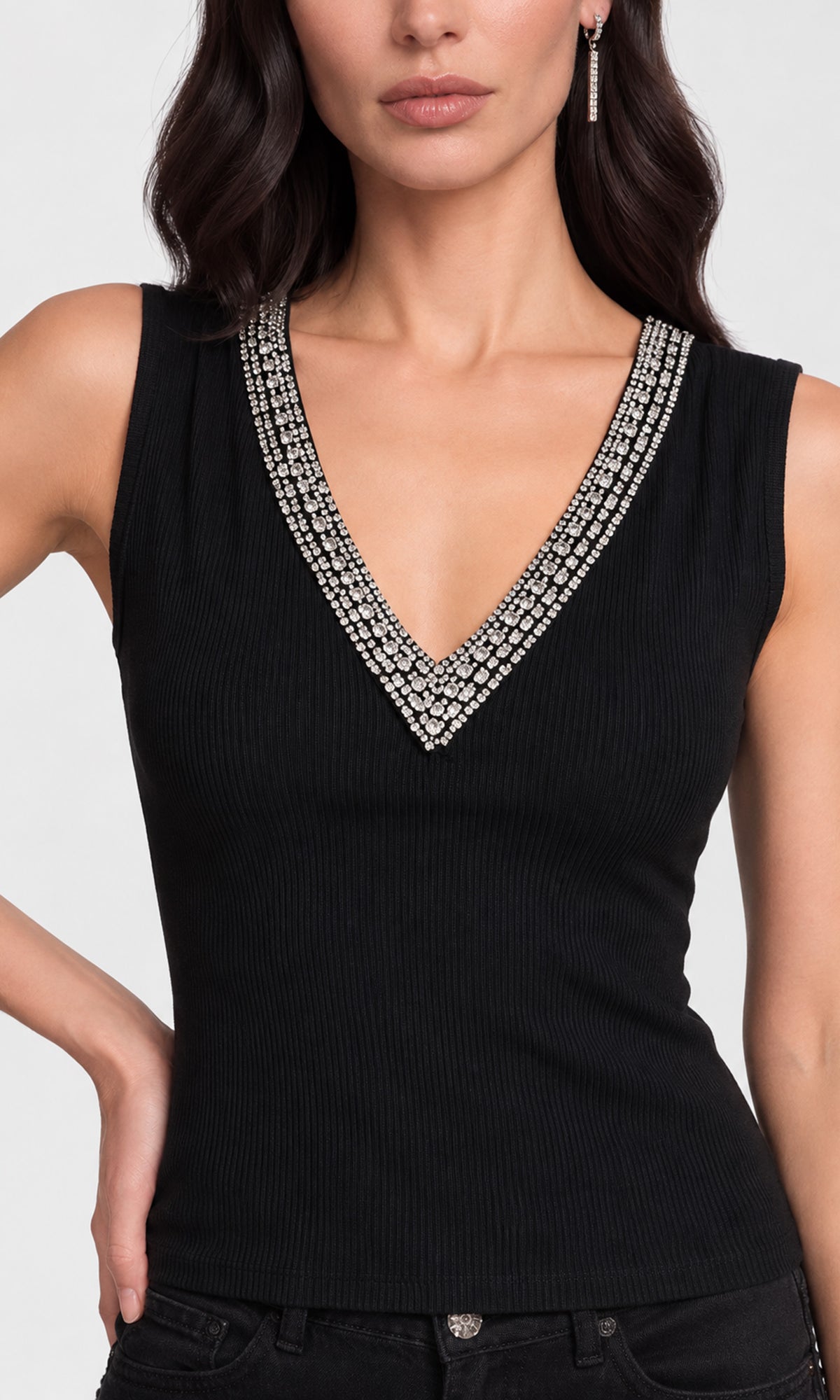 A close-up of a woman wearing a black ribbed sleeveless V-neck top with a wide, embellished silver rhinestone collar trim.
