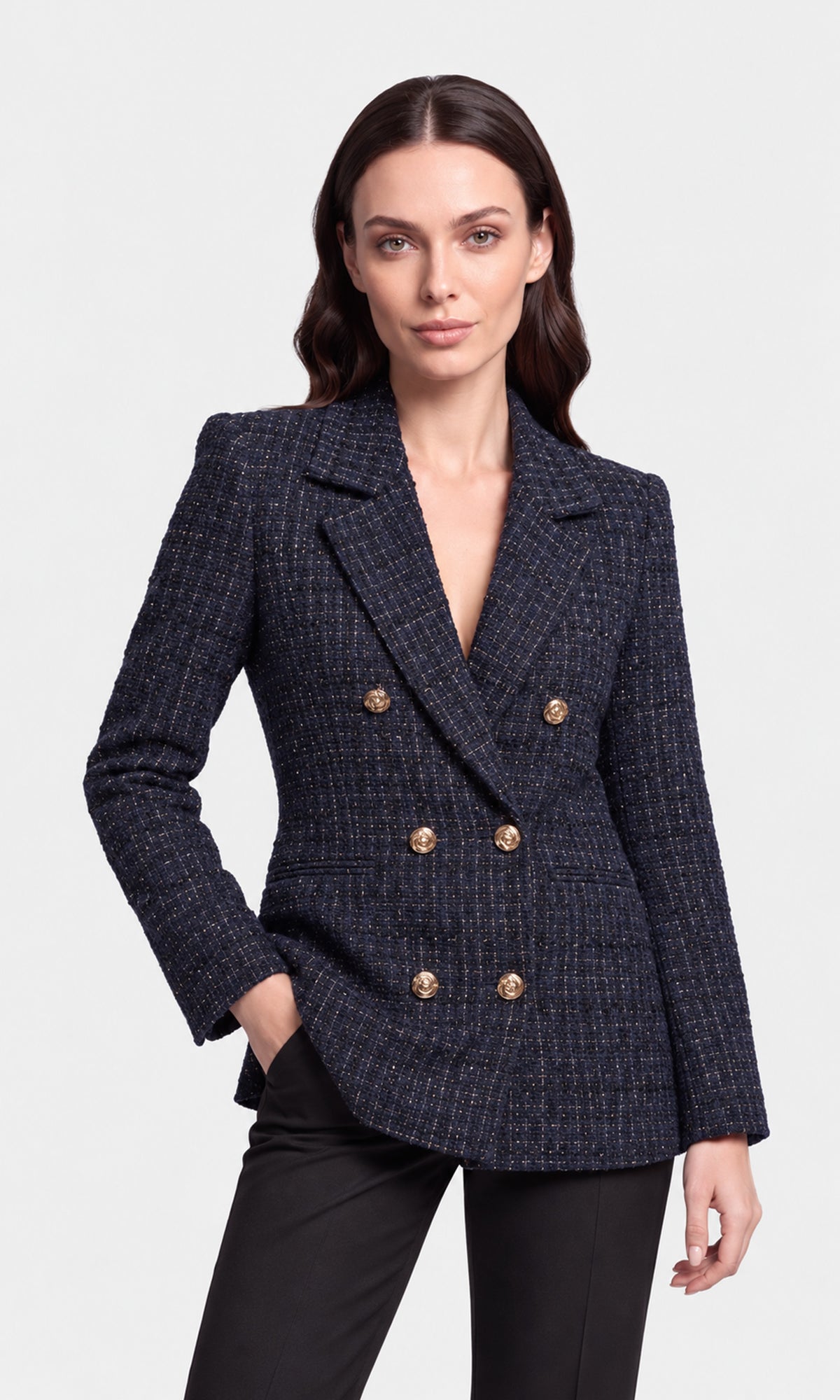 A woman modeling a dark navy blue double-breasted blazer with a subtle tweed pattern and gold buttons, paired with black pants.