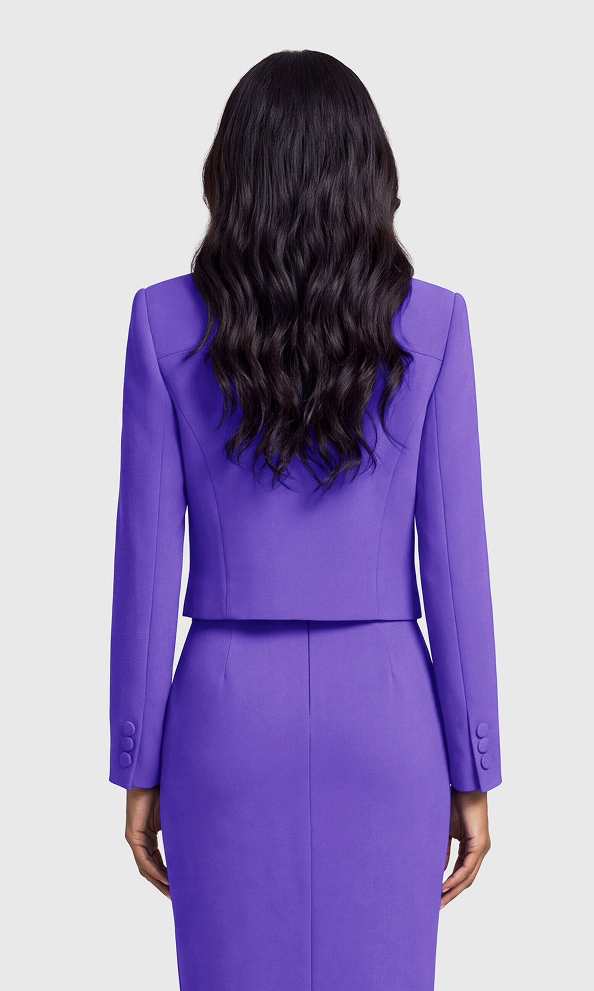 A woman shown from the back wearing a matching purple tailored jacket and skirt.