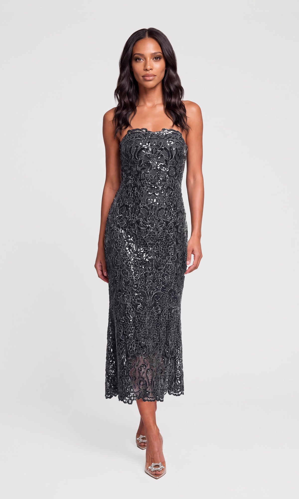 Model wearing a strapless black sequined midi dress with a fitted silhouette and lace-like texture.