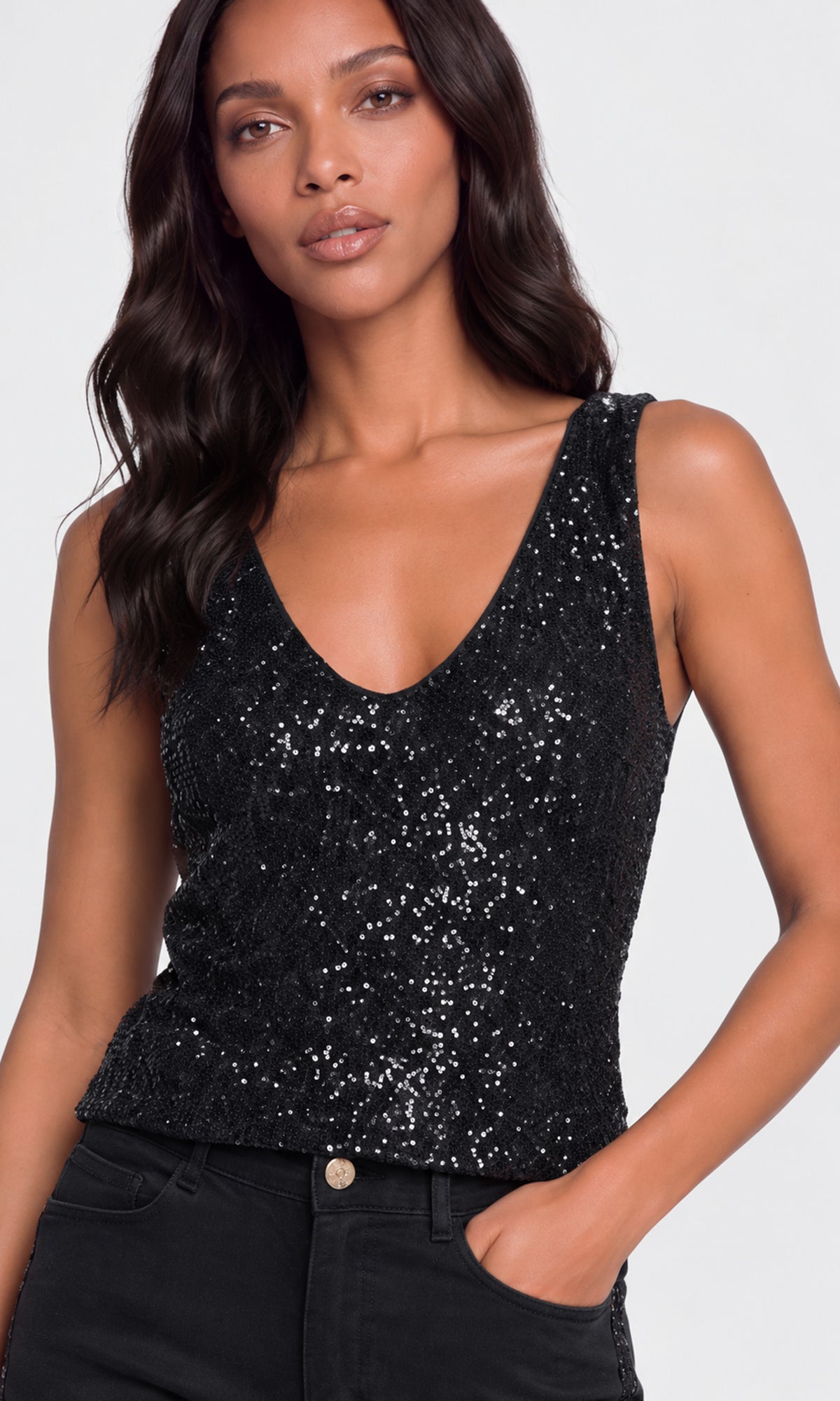 Close-up of a sleeveless black sequined tank top with a deep V-neck and black jeans.