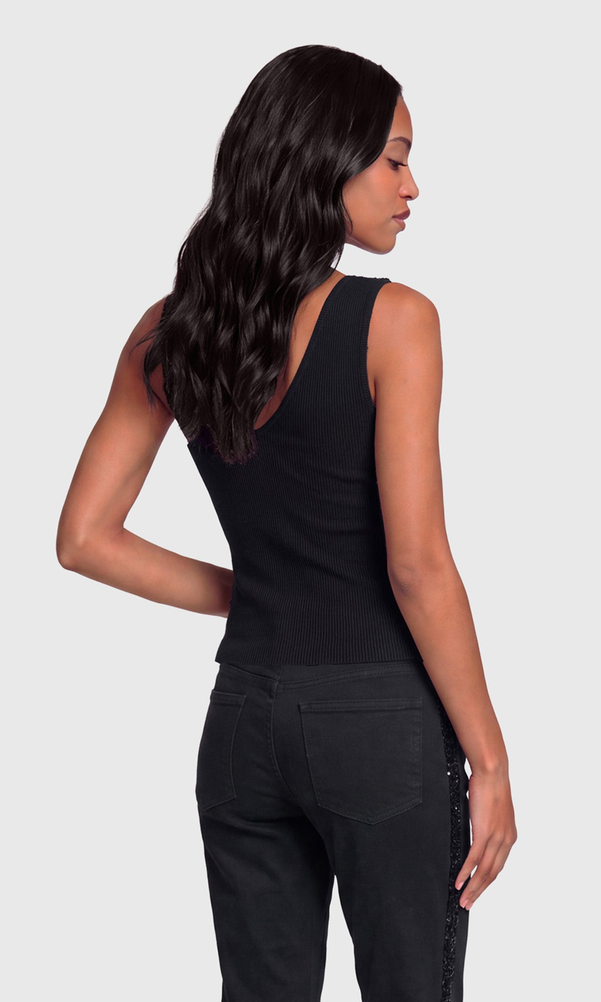 Back view of model wearing a black sleeveless top and black pants.