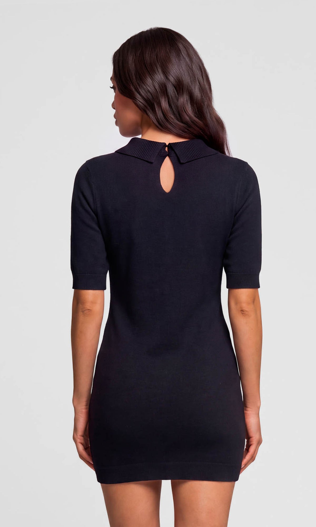 Back view of model wearing a short-sleeve black knit mini dress with a keyhole cutout at the neck.