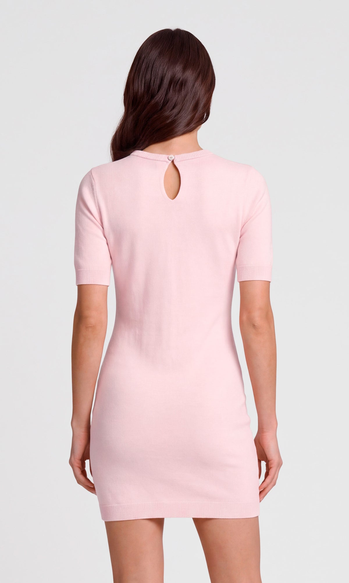 A woman viewed from the back wearing a light pink short-sleeve knit dress with a small keyhole cutout at the neckline.