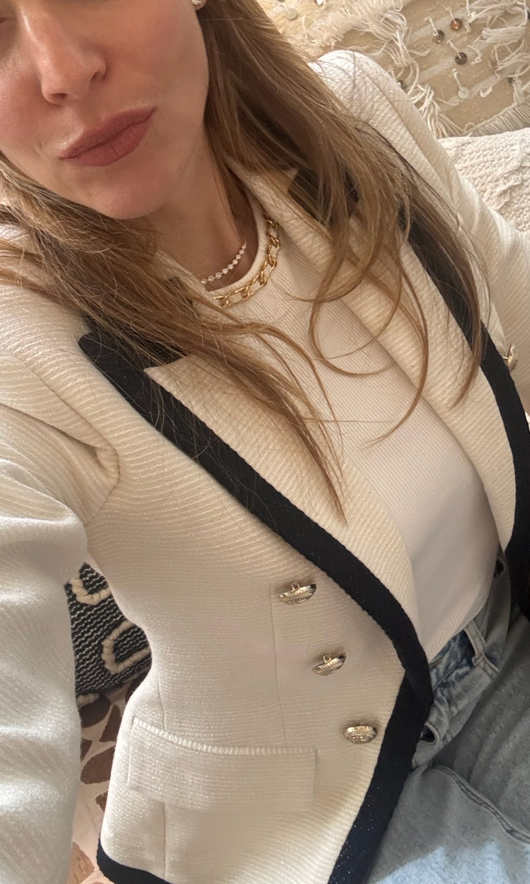 Close-up of a person wearing a cream-colored blazer with black trim.