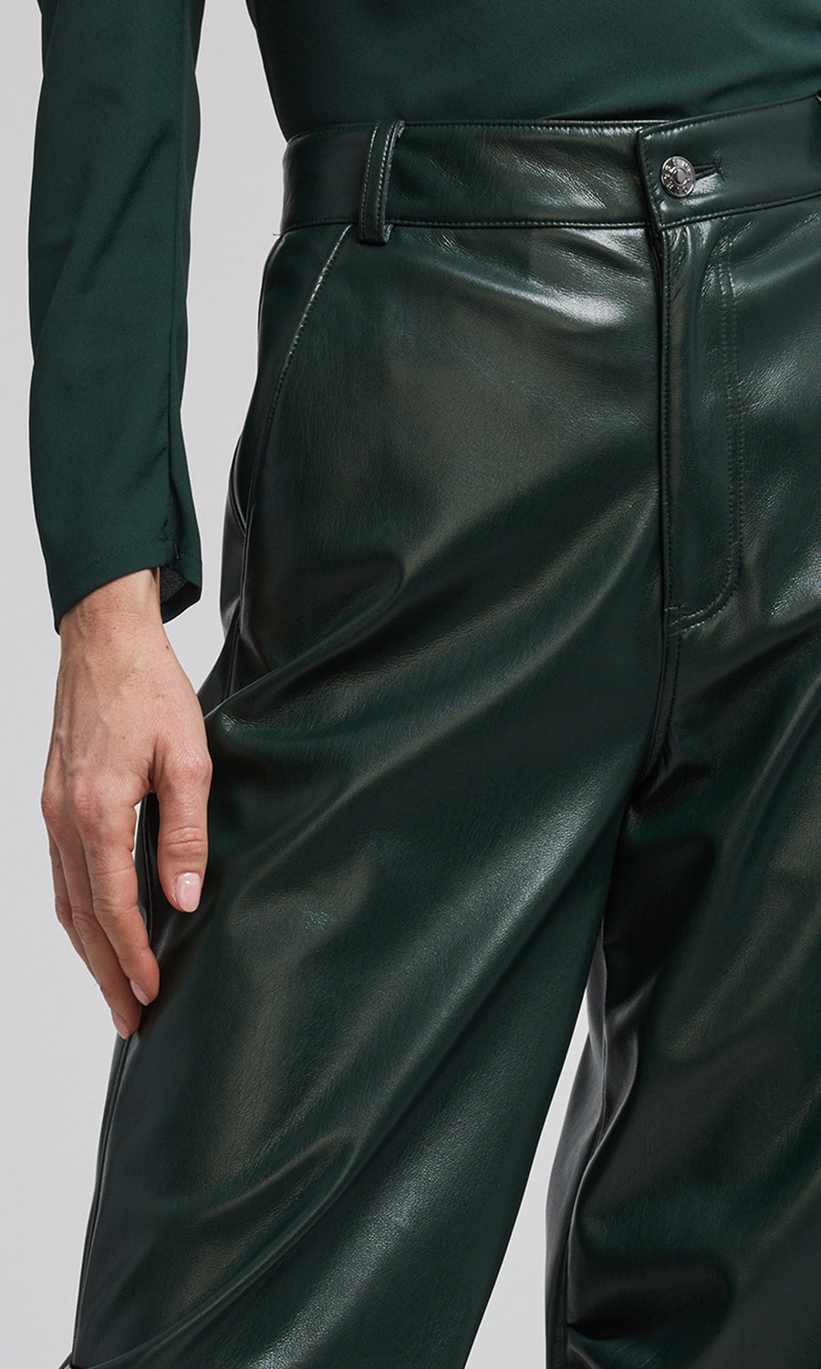 A woman models vibrant green vegan leather jogger pants, highlighting a chic and sustainable clothing option.