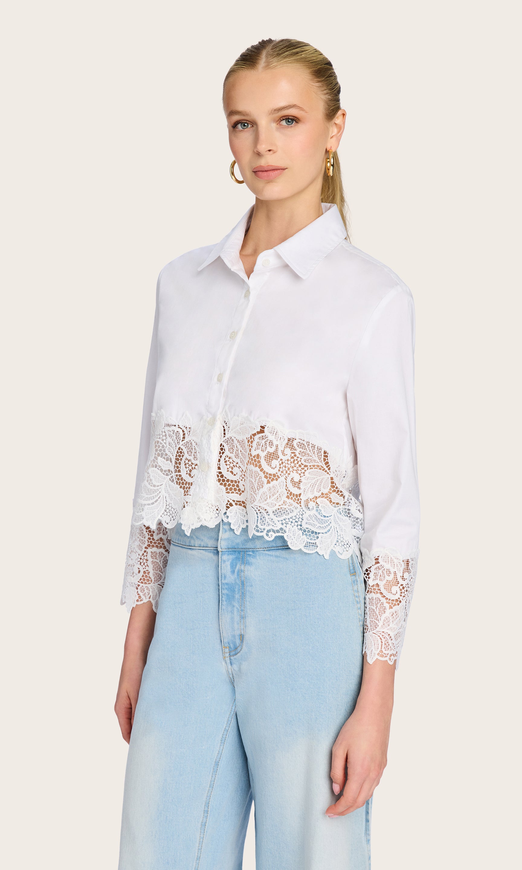 3/4 front view of the model wearing the Issa Lace Combo Shirt, paired with light-wash denim to highlight the intricate lace hem and cuffs.