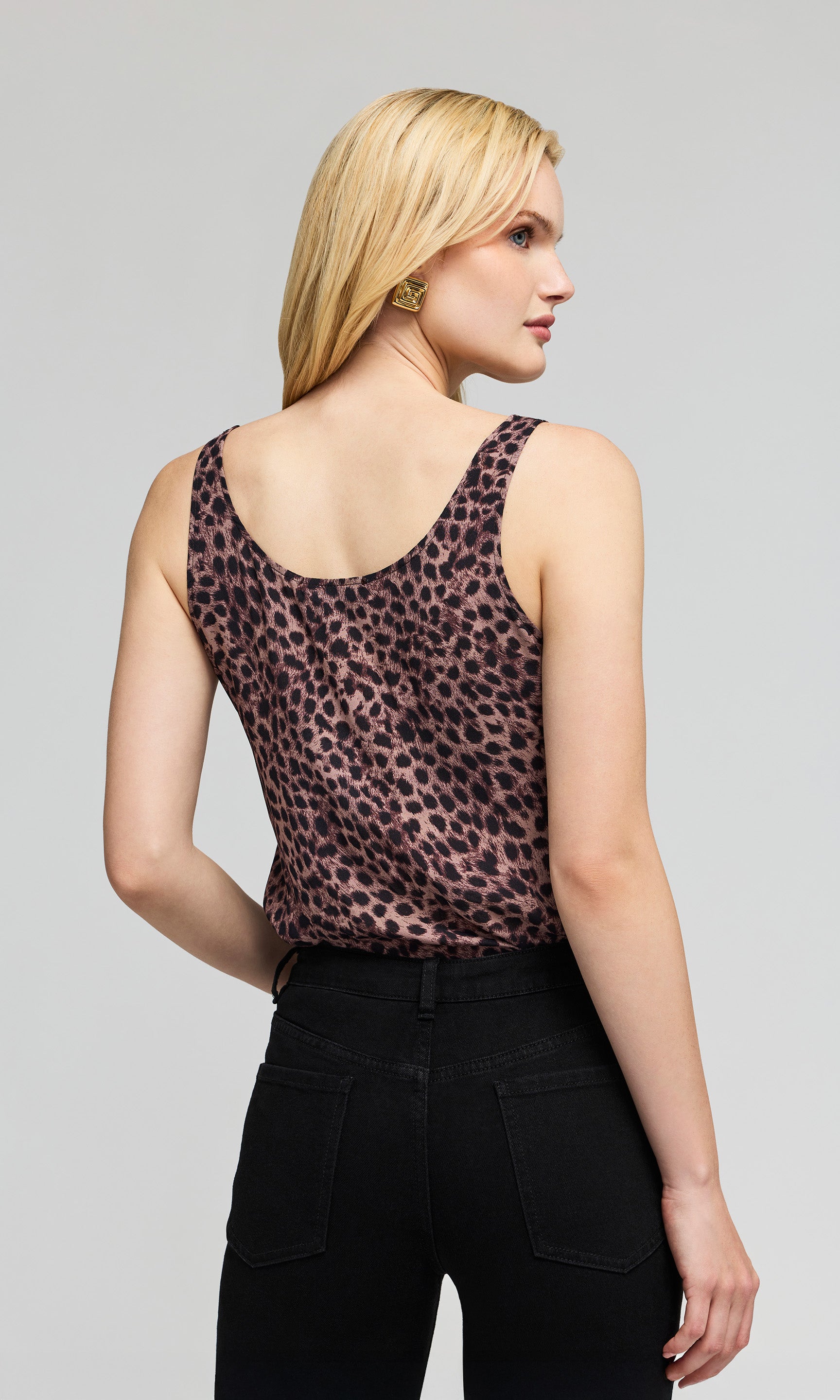 Back view of model wearing a sleeveless brown  leopard print pattern top, paired with black pants, on a plain background.