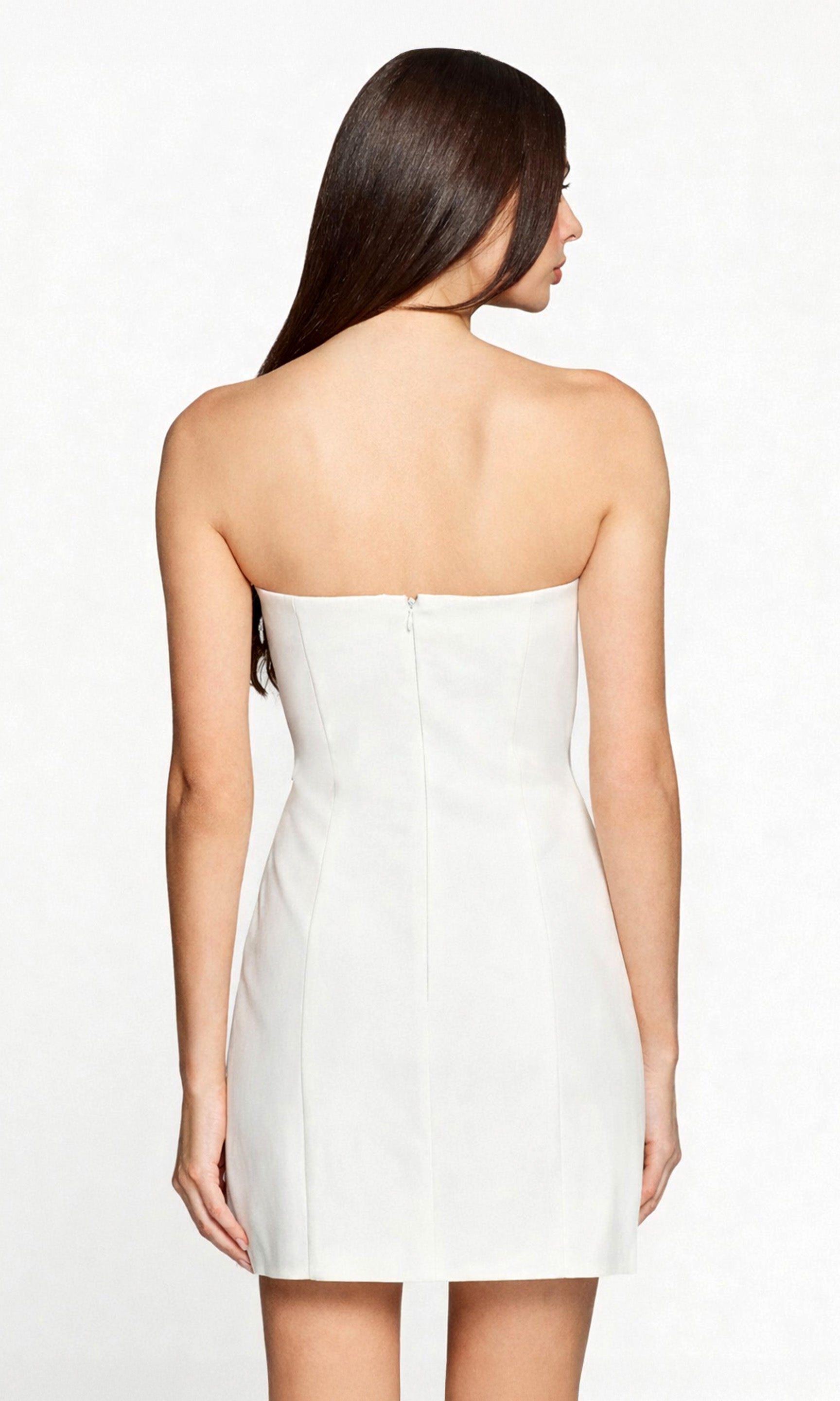 Woman wearing a white strapless dress on a plain background