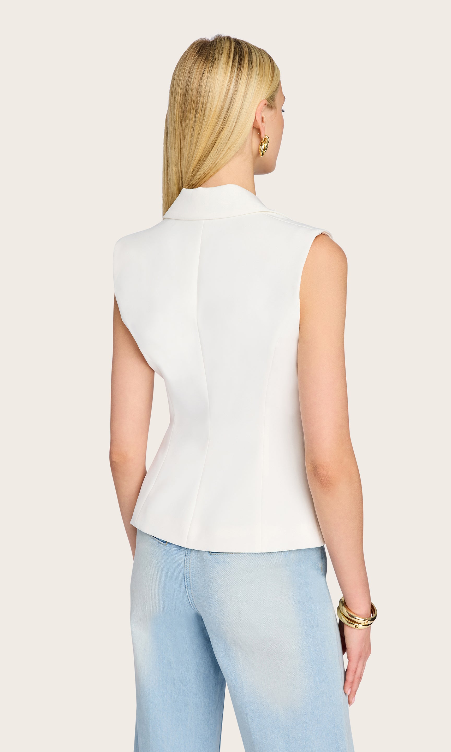 From the back view, the model highlights the flattering cinched waist and minimalist seam details of the Jenna Sleeveless Blazer, bringing focus to its tailored structure.