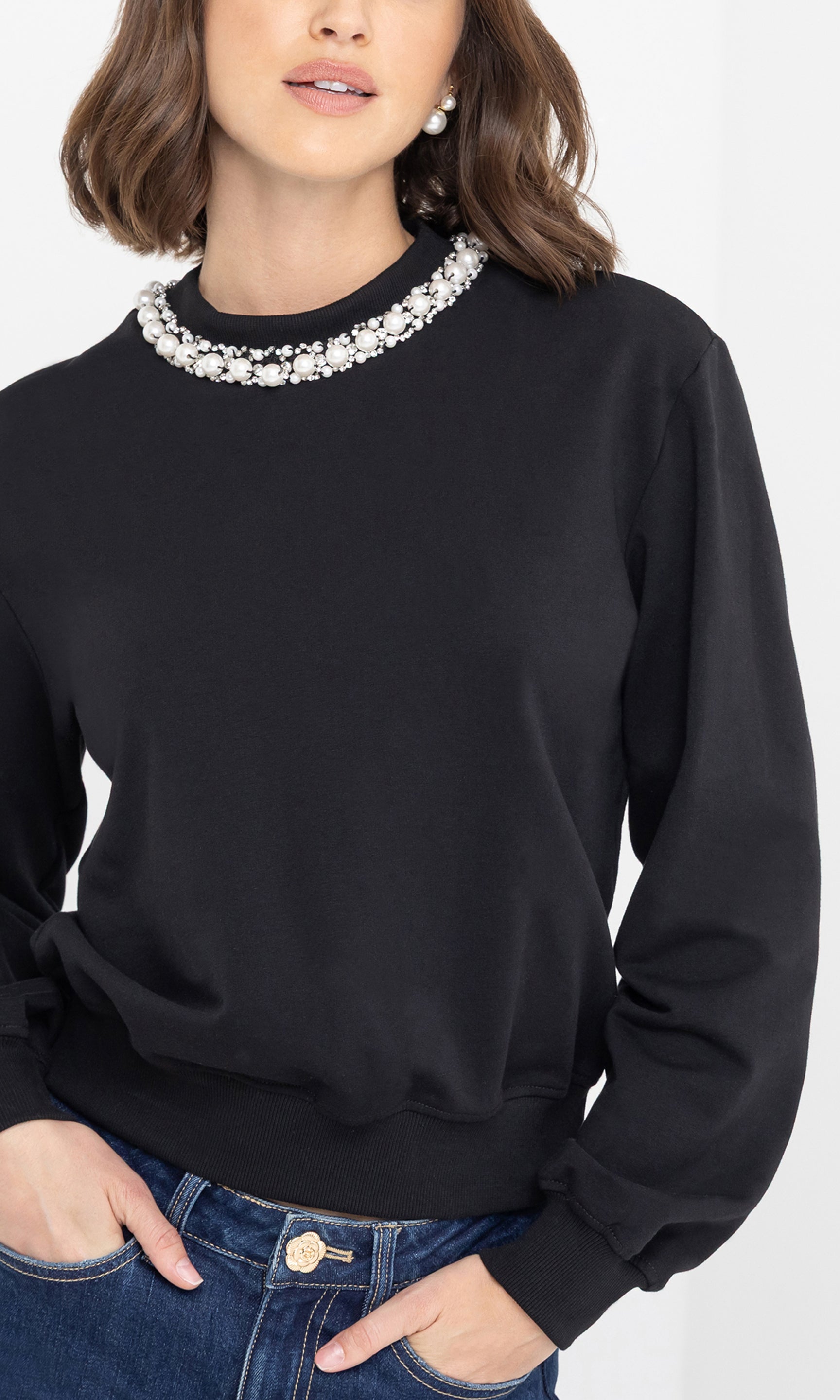 Person wearing a black sweater with a decorative collar on a white background