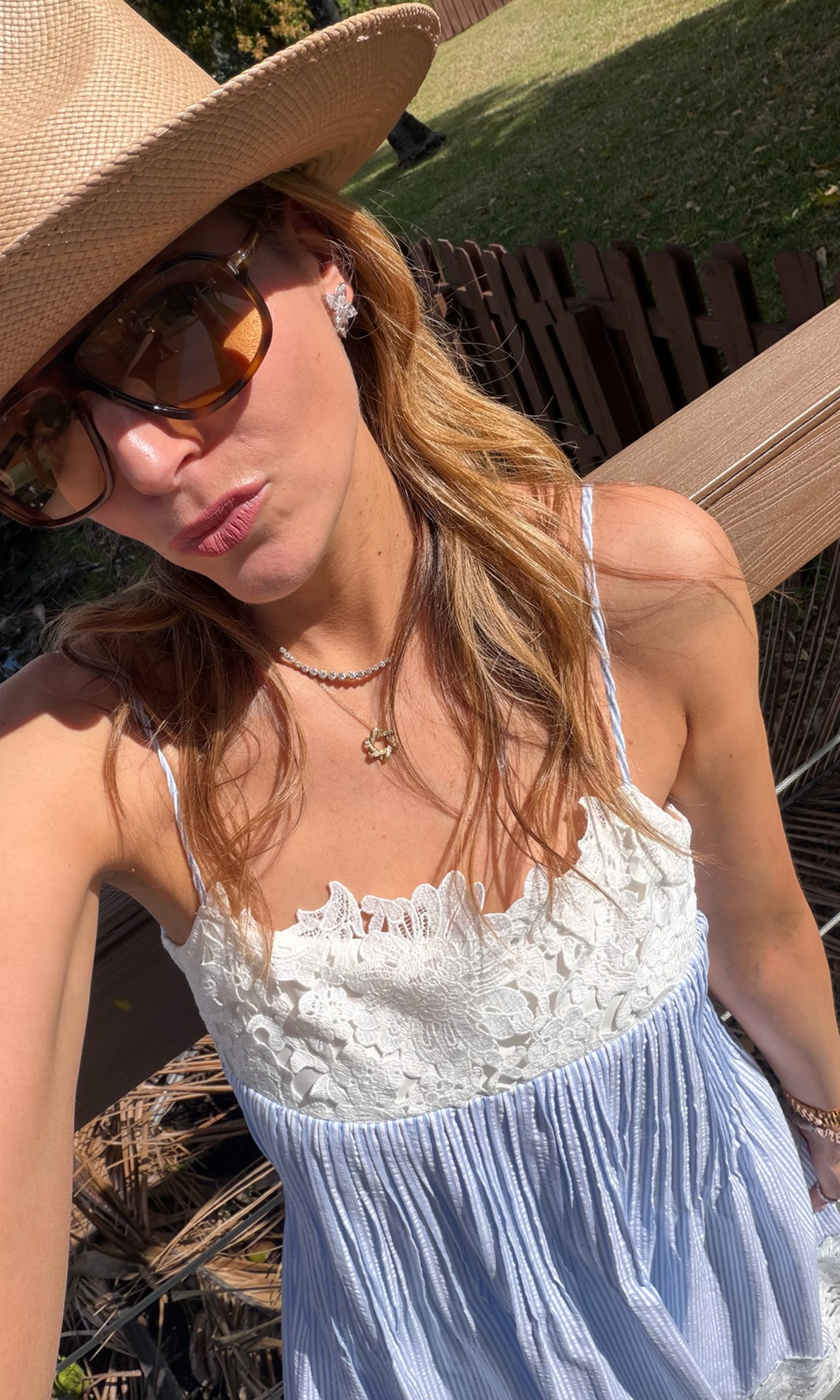 Woman wearing a summer dress with a straw hat outdoors.