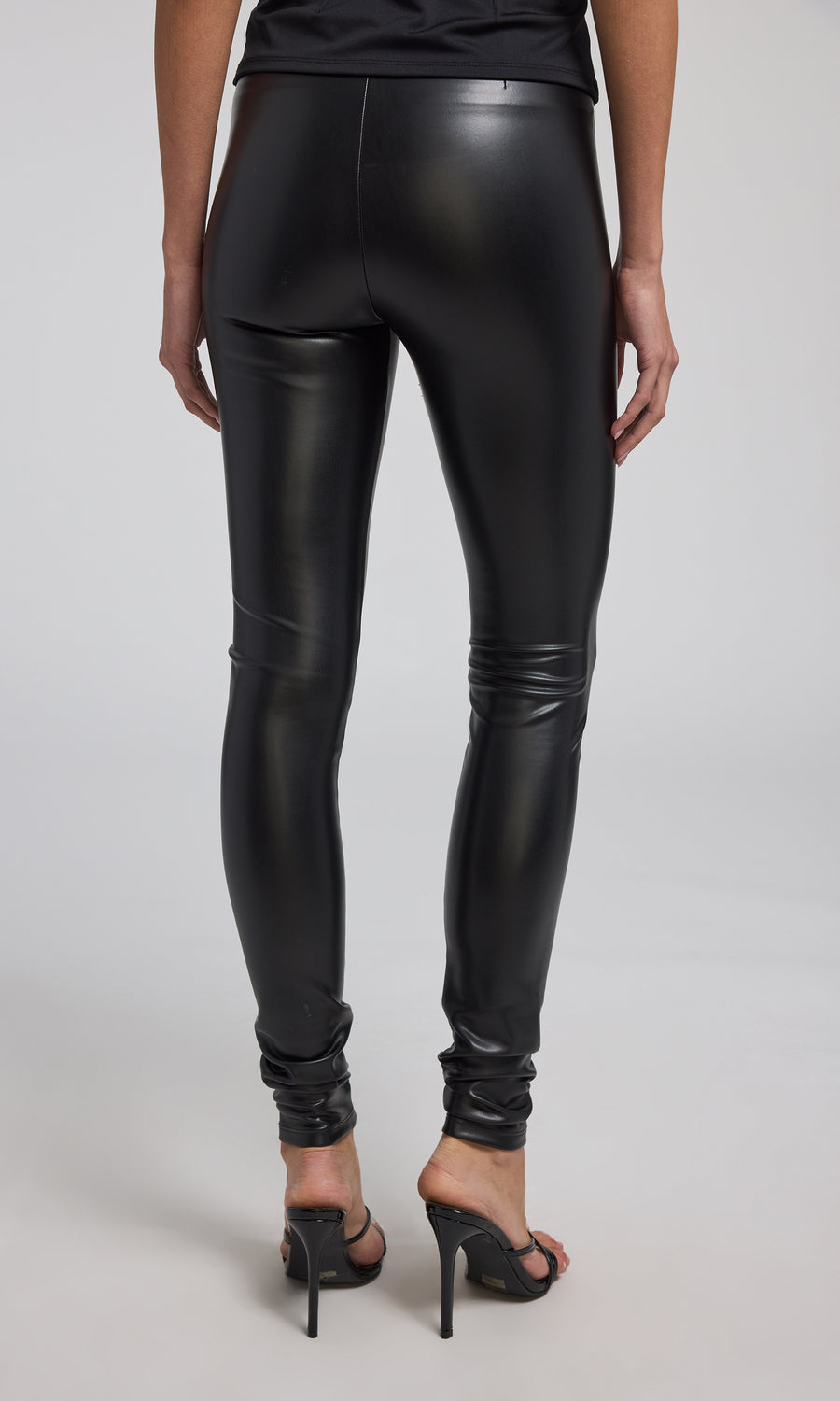 Stretchy black vegan leather leggings designed for a sleek fit, perfect for versatile fashion choices.