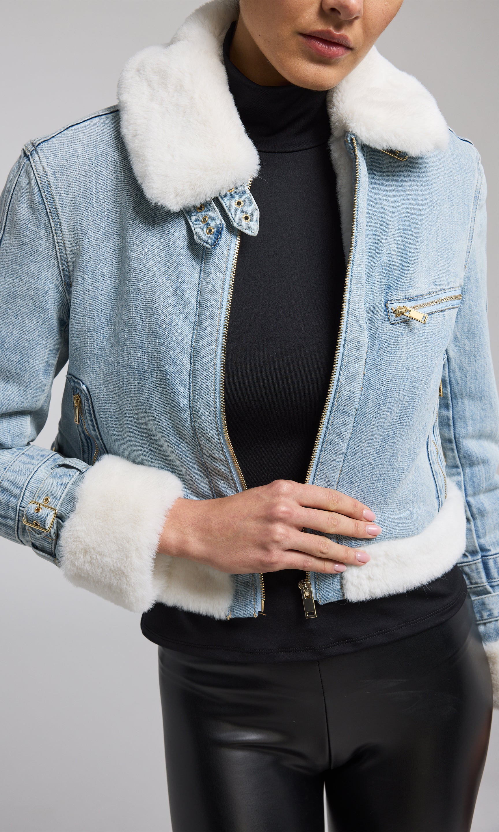 A model showcases a stylish denim jacket featuring a luxurious faux fur collar, blending casual and chic elements.