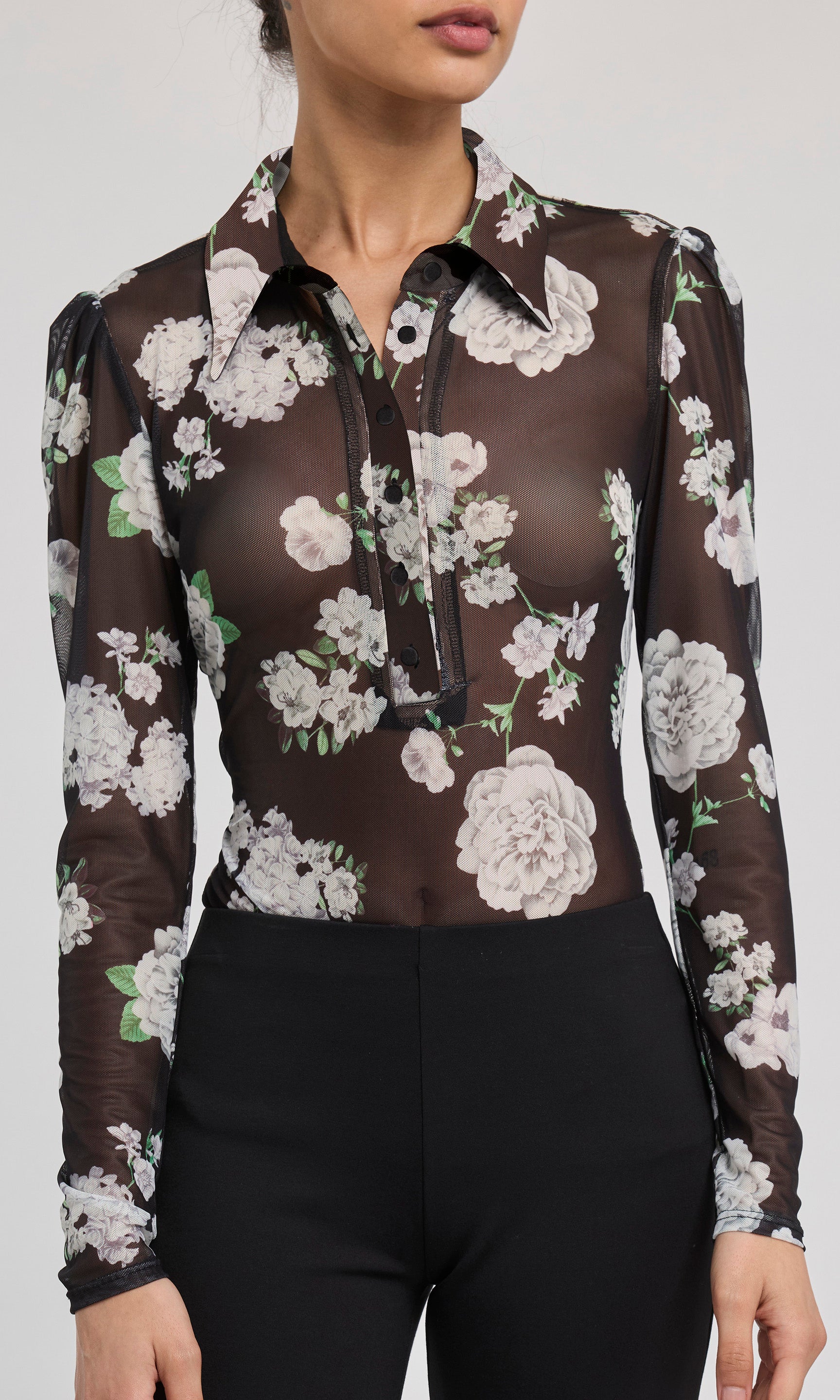 Sheer floral blouse with black base worn by a model on a white background