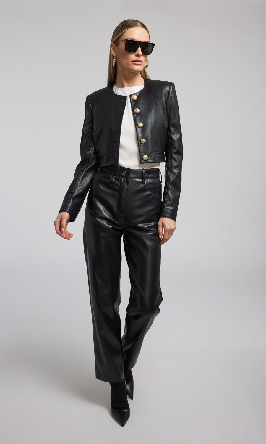 A cropped black vegan leather blazer featuring front buttons, showcasing a stylish and modern design.