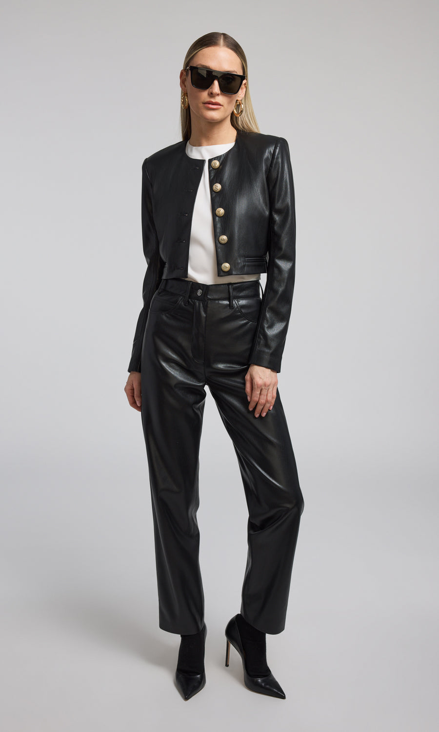 A cropped black vegan leather blazer featuring front buttons, showcasing a stylish and modern design.