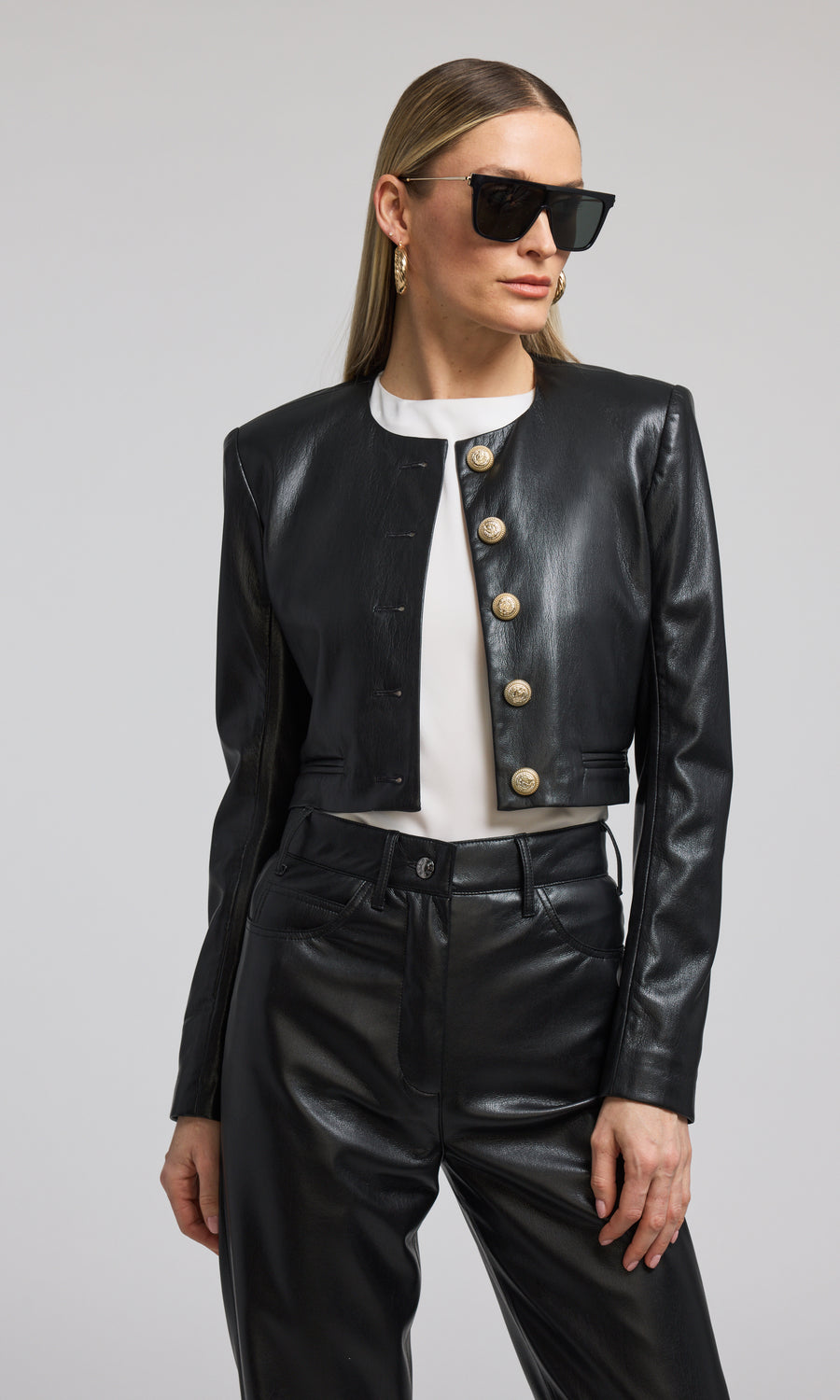 A cropped black vegan leather blazer featuring front buttons, showcasing a stylish and modern design.