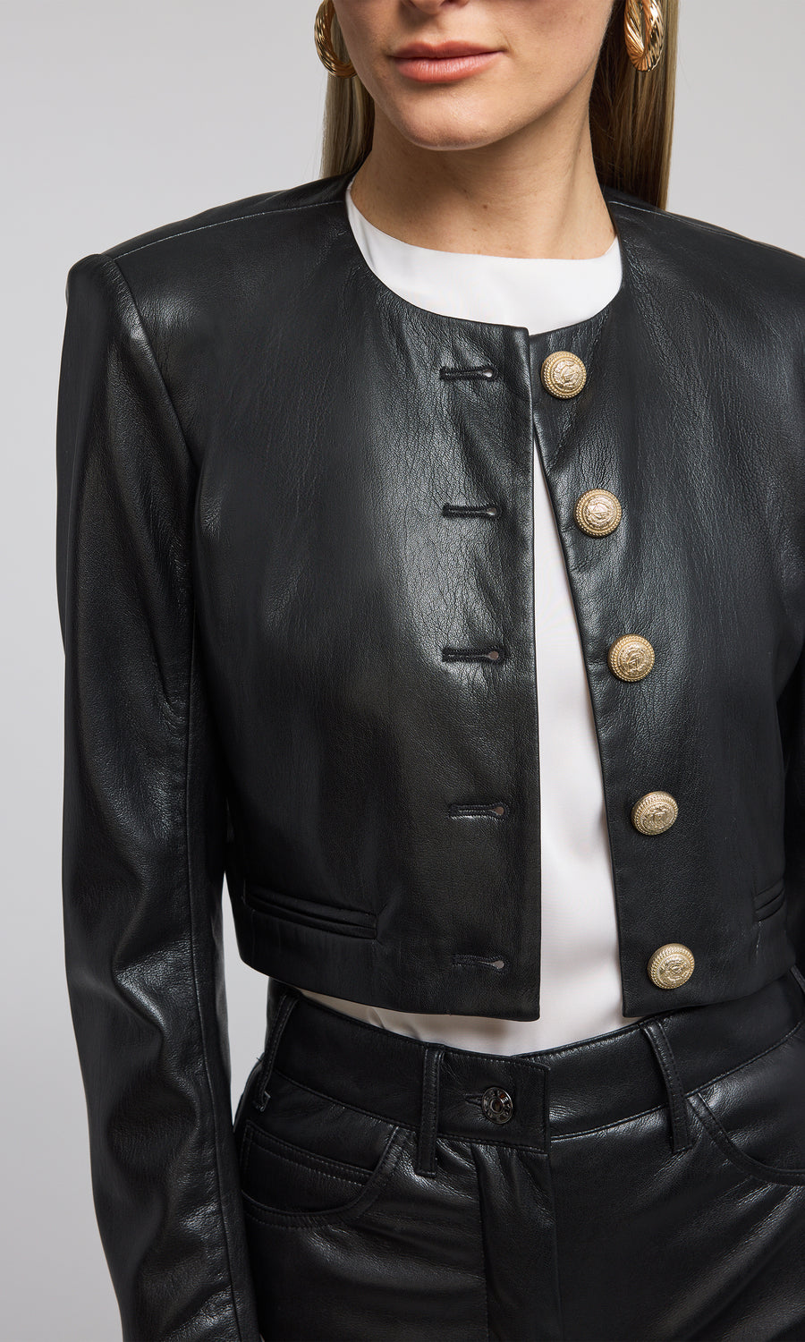 A cropped black vegan leather blazer featuring front buttons, showcasing a stylish and modern design.