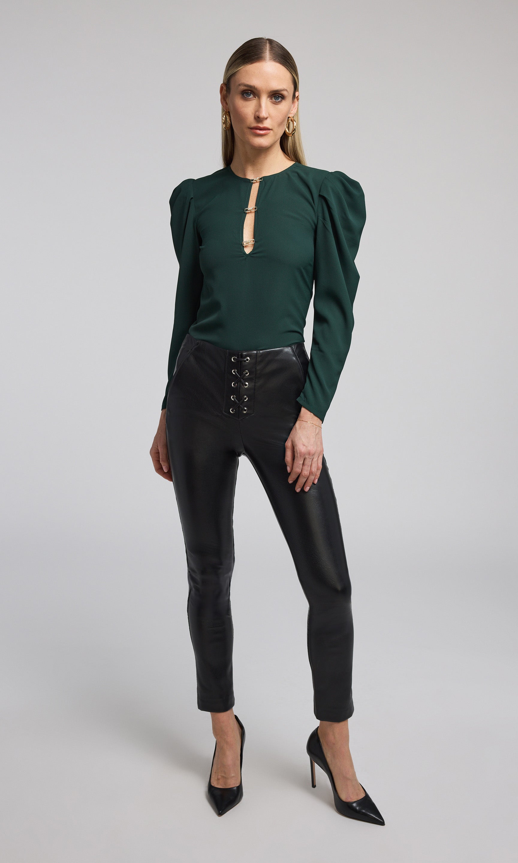 A model showcases vegan leather lace-up leggings featuring intricate lace detailing, emphasizing a stylish and edgy look.