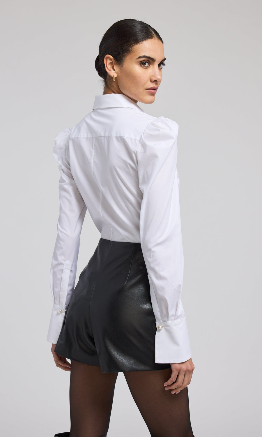  A model presents a fashionable white shirt, drawing attention to its clean lines and timeless style.