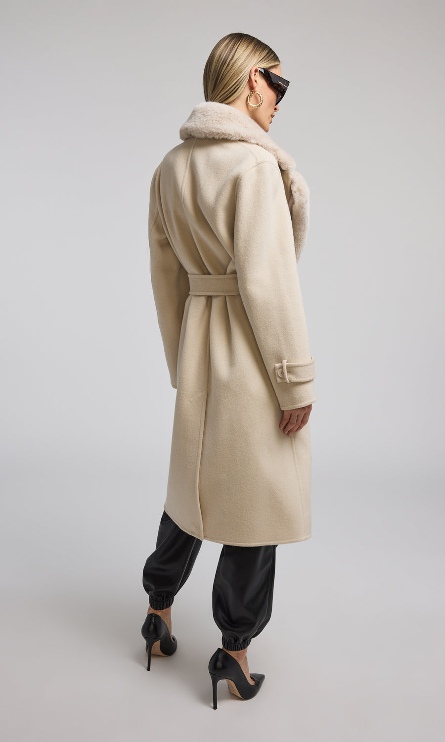 The image features a model in a chic beige coat adorned with a plush fur collar, highlighting a blend of comfort and style.