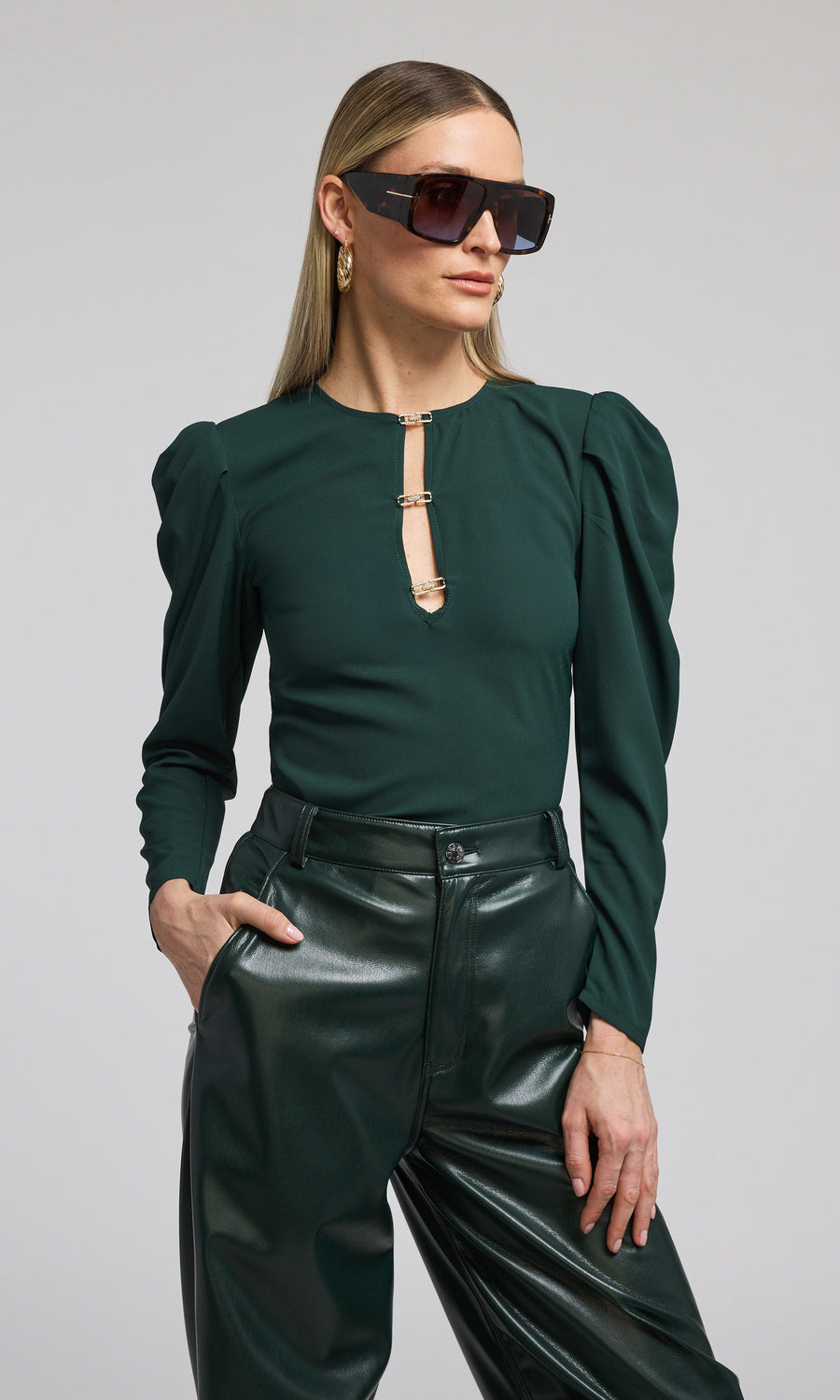 The model presents a striking green blouse, accentuating its unique design and lively color.