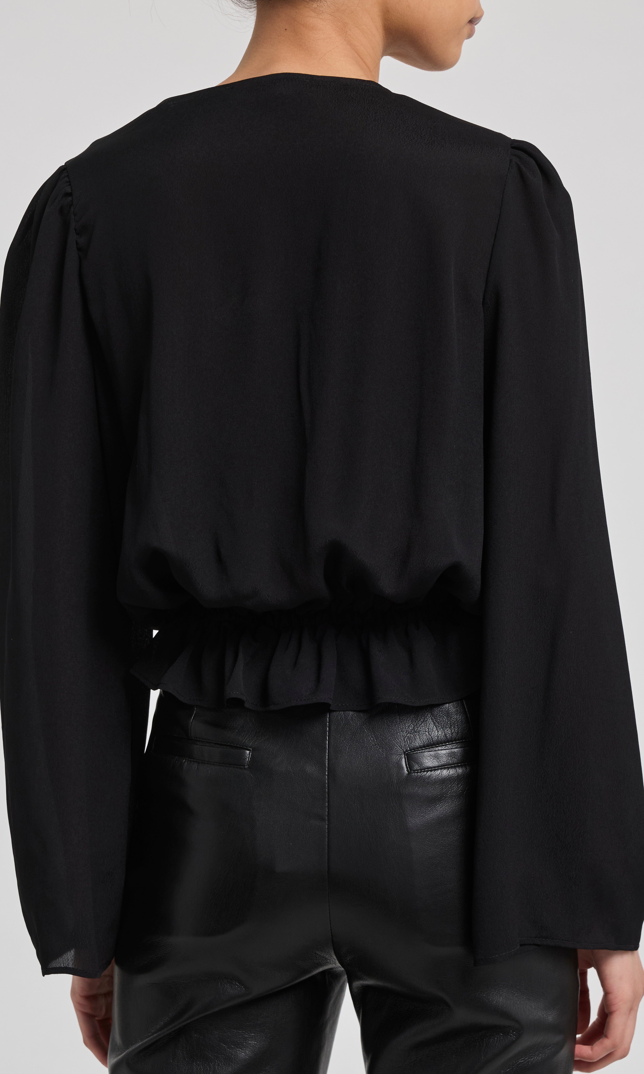 Black long-sleeve top worn by a person on a white background