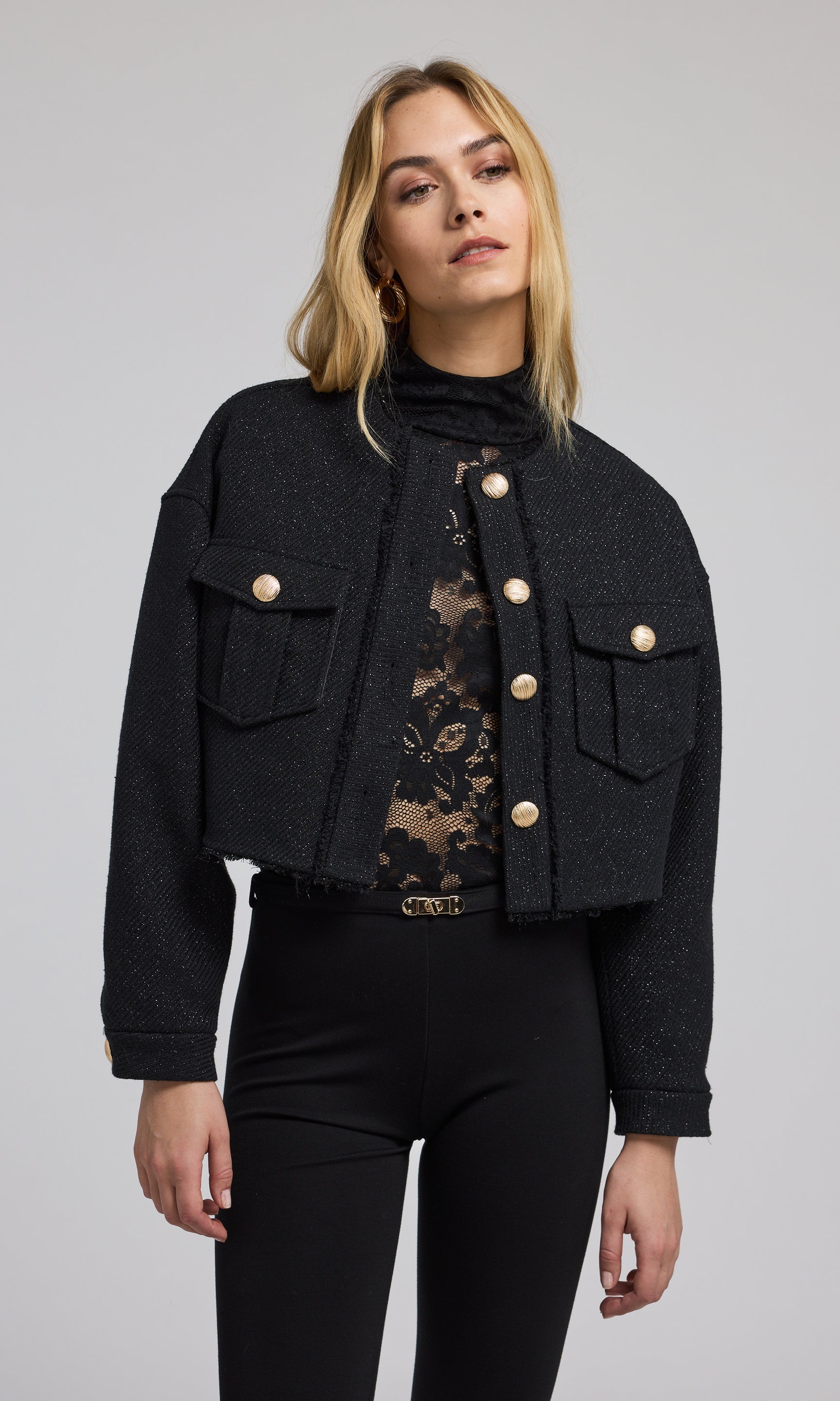 A stylish black cropped bomber jacket with gold buttons, emphasizing a modern and elegant look in outerwear fashion.